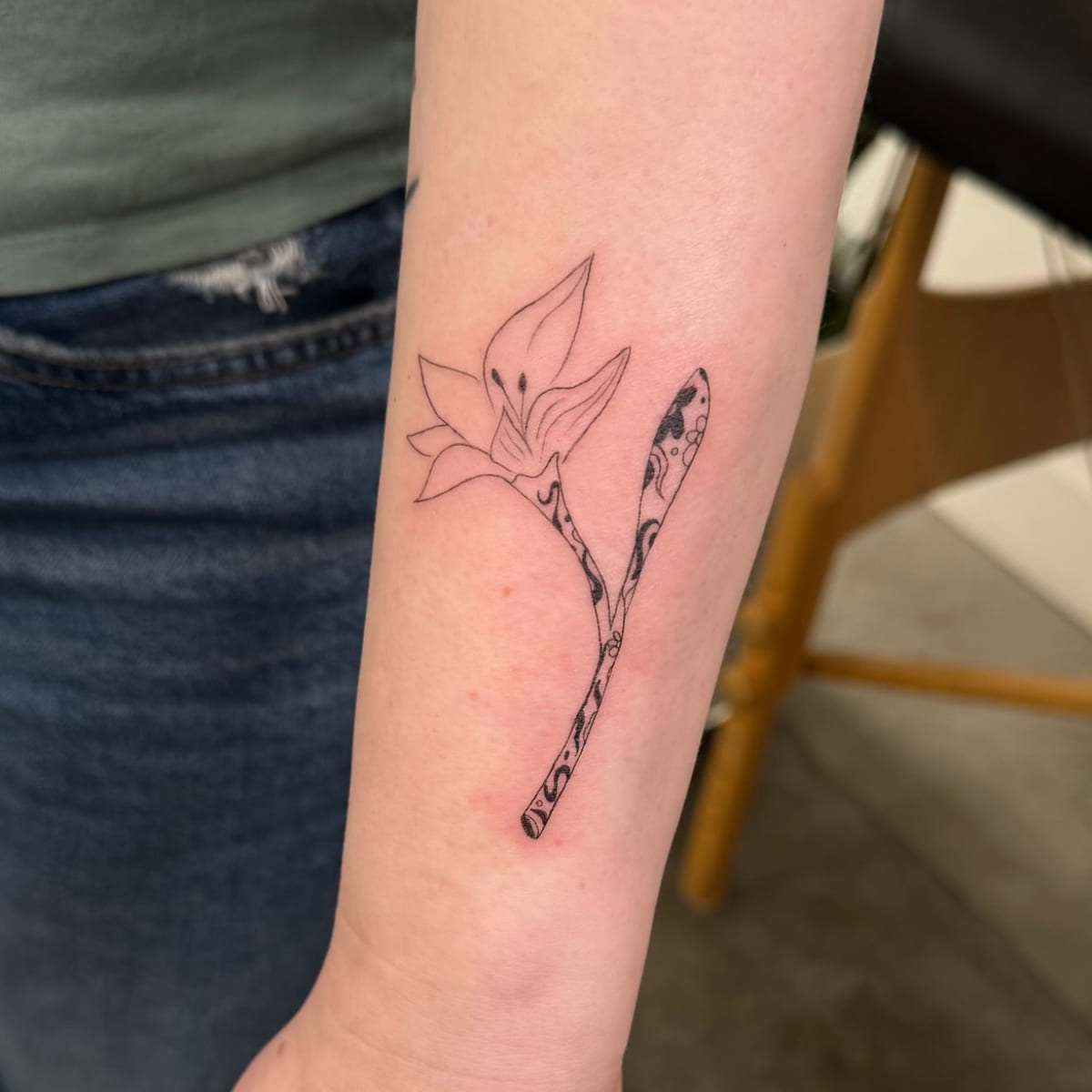 Magnolia on a patterned stem, fine line tattoo