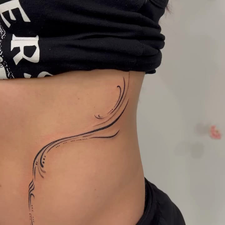 Ornamental flowing lines framing both sides of the abdomen, fine line tattoo