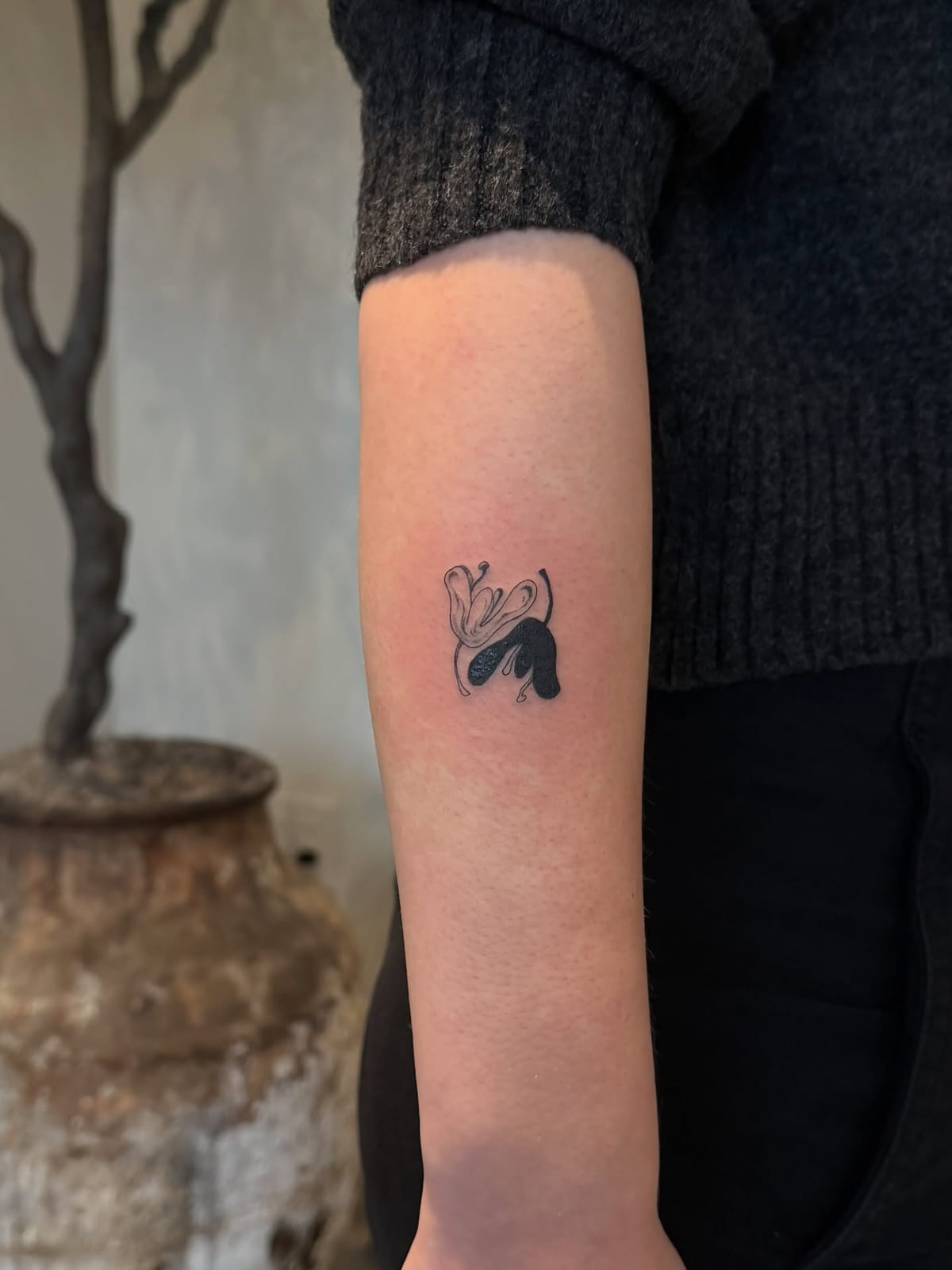 Abstract solid black shape with a floral swirl, fine line tattoo