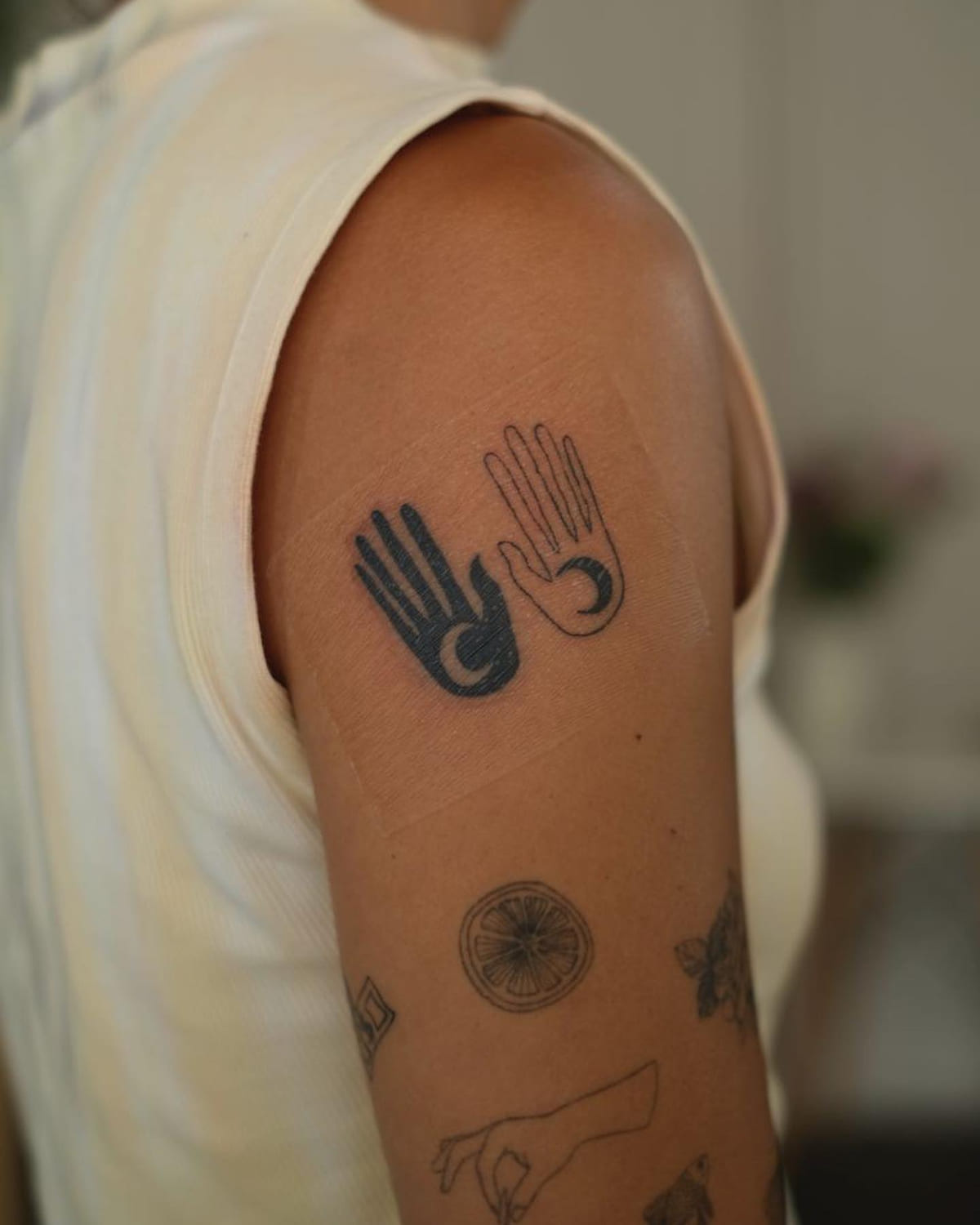 Pair of hands with crescent moons, one solid and one outline, fine line tattoo