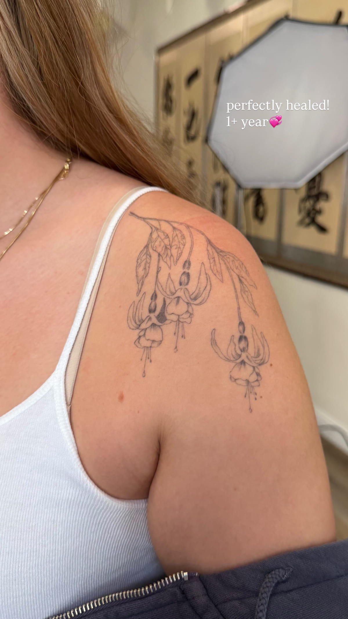 Floral with hanging ornaments on a shoulder blade, healed fine line tattoo