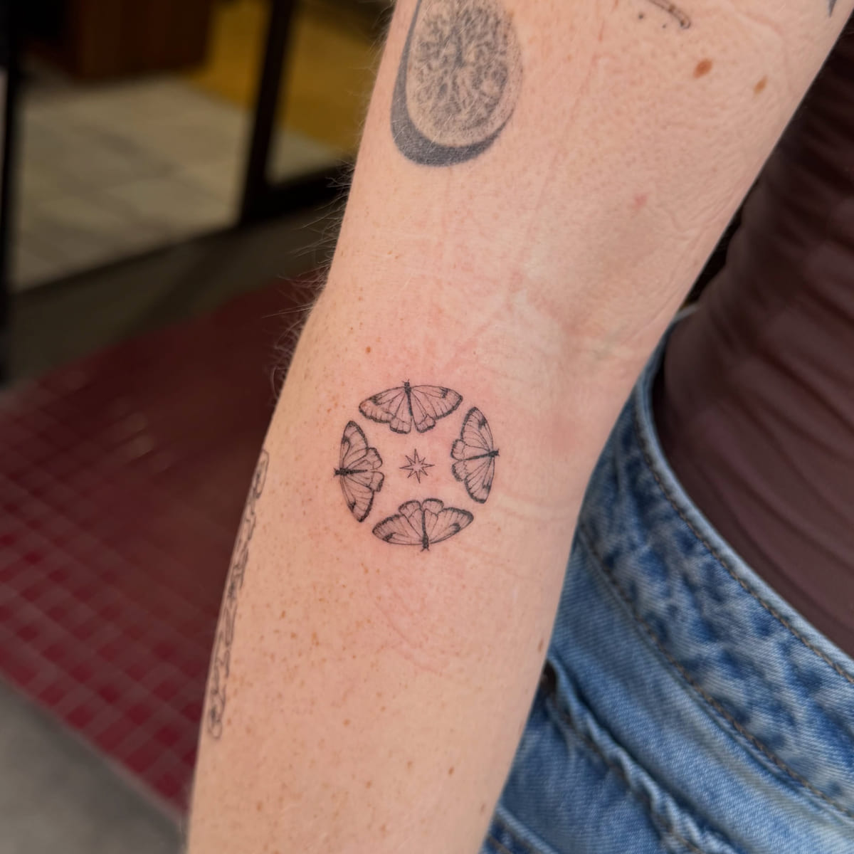 Ring of four butterflies around a star, fine line tattoo