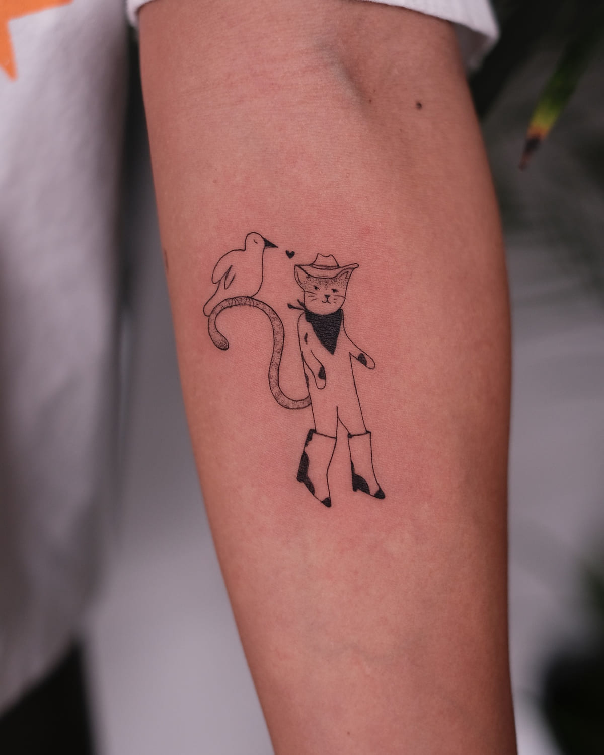 Cat in a cowboy hat and boots with a bird on its tail, fine line tattoo