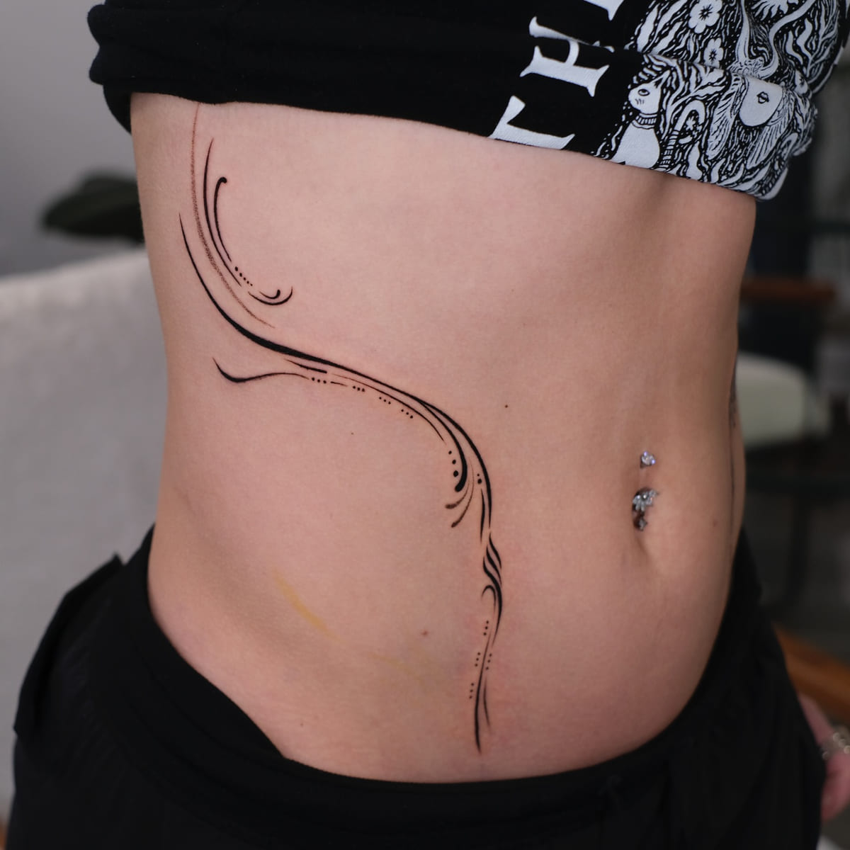 Ornamental flowing lines framing both sides of the abdomen, another view