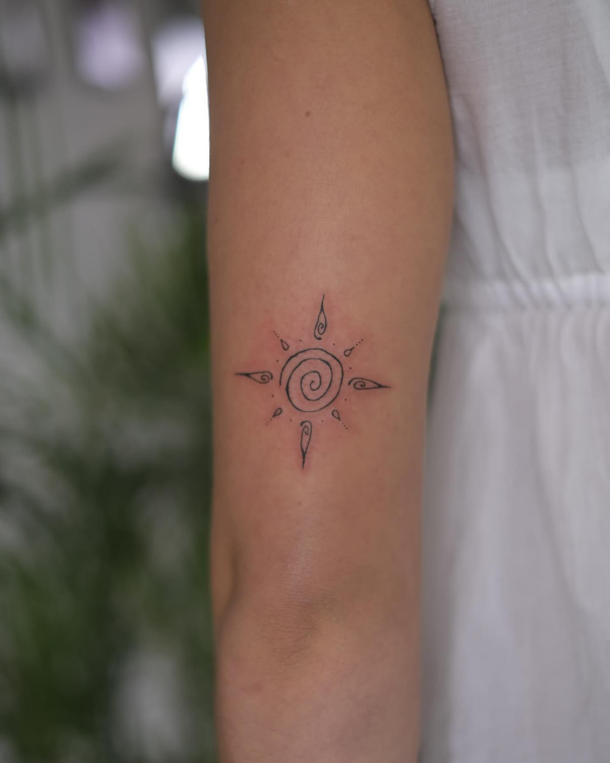 Spiral sun with pointed rays, fine line tattoo