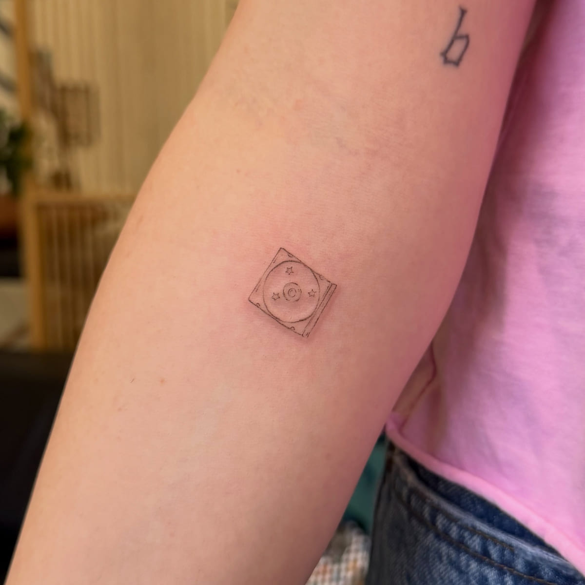 Tiny CD in a jewel case, fine line tattoo