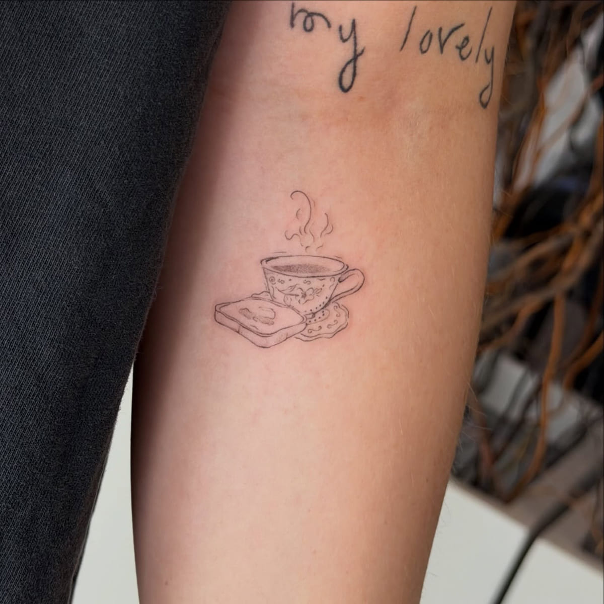 Steaming teacup on a book, fine line tattoo