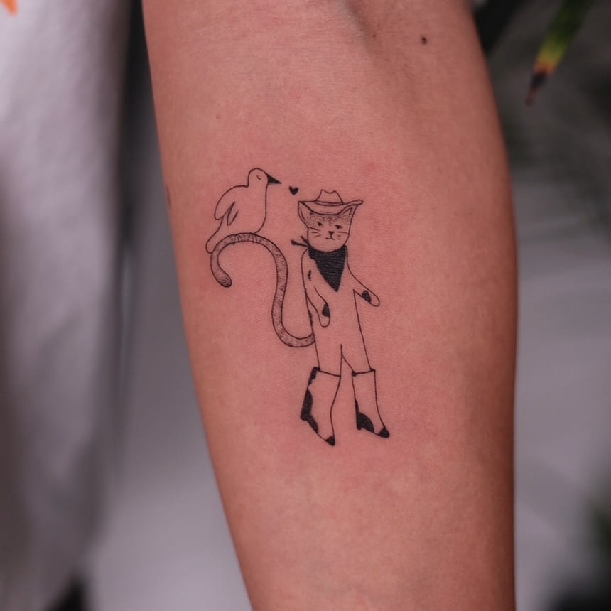 Cat in a cowboy hat and boots with a bird on its tail, another view