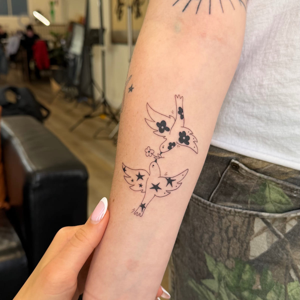 Two birds filled with flowers and stars, fine line tattoo