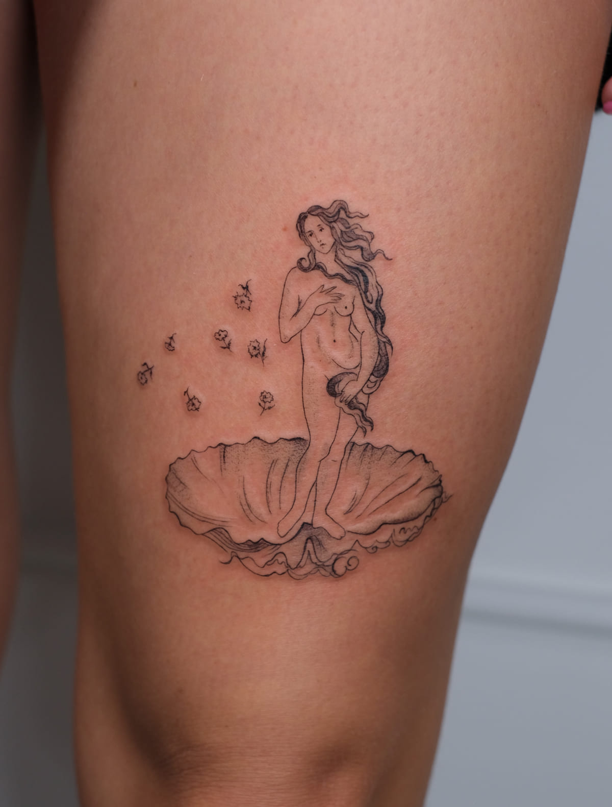 Birth of Venus on a shell with falling roses, fine line tattoo