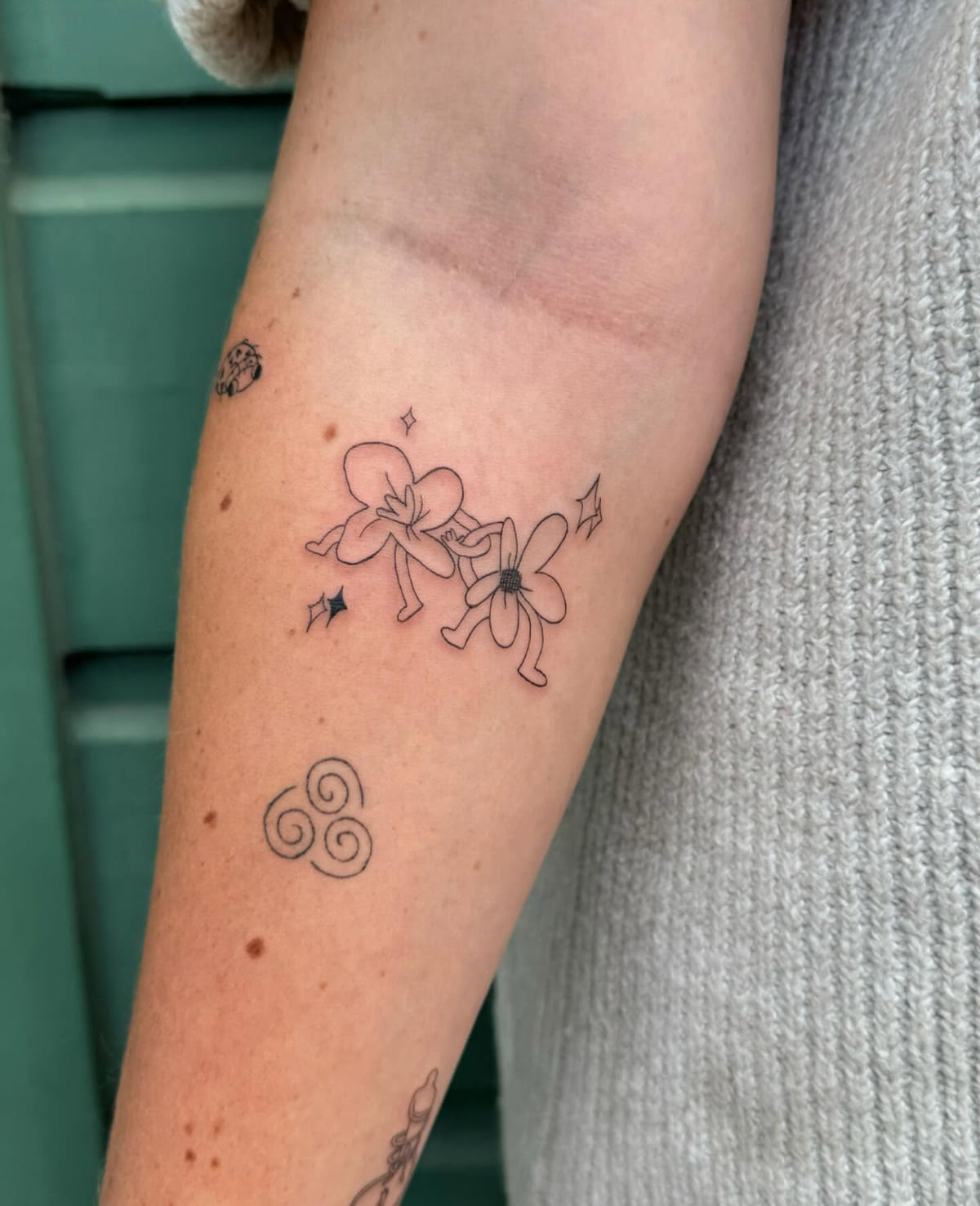 Two flower characters holding hands with sparkles, fine line tattoo