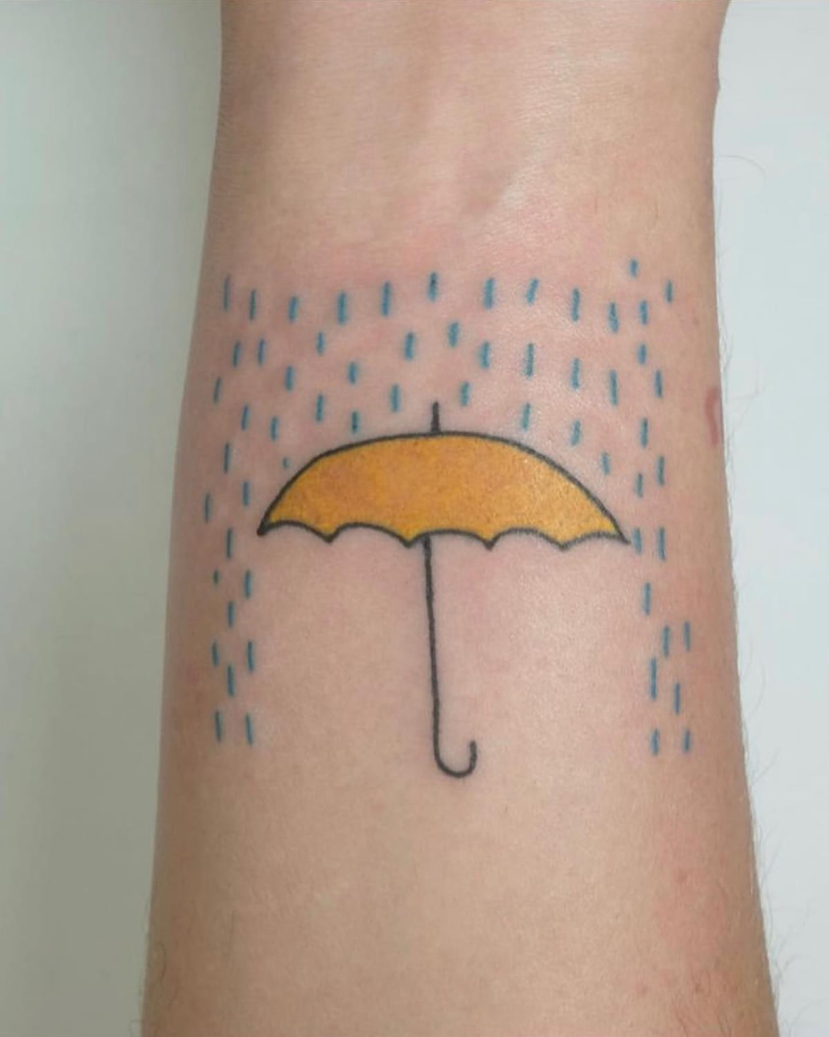Yellow umbrella under blue rain, healed fine line tattoo