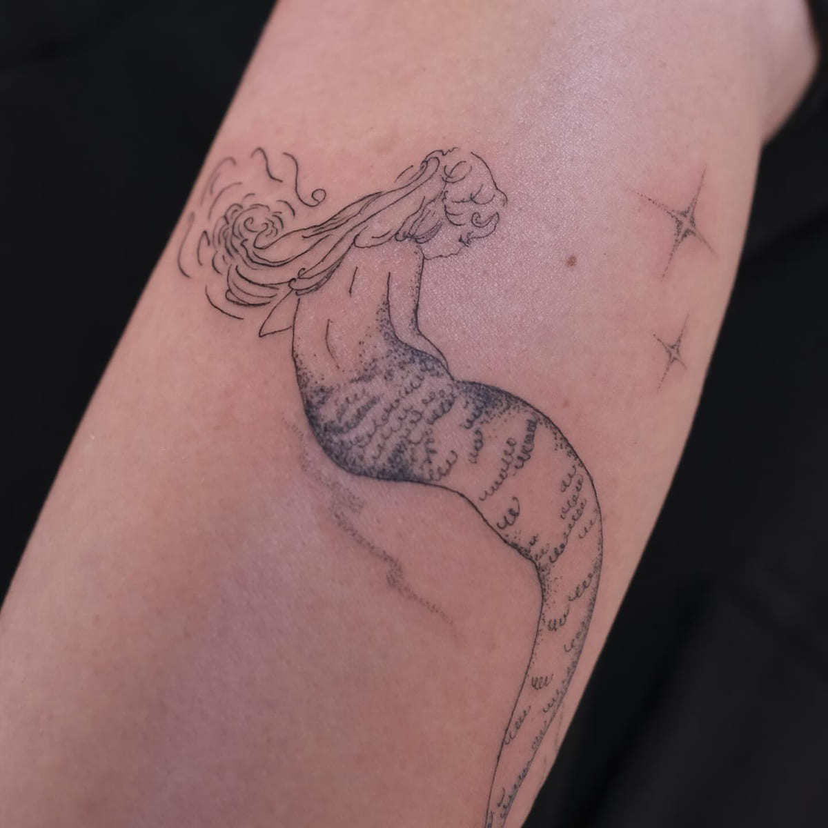 Mermaid seen from behind with wind swept hair and sparkles, another view