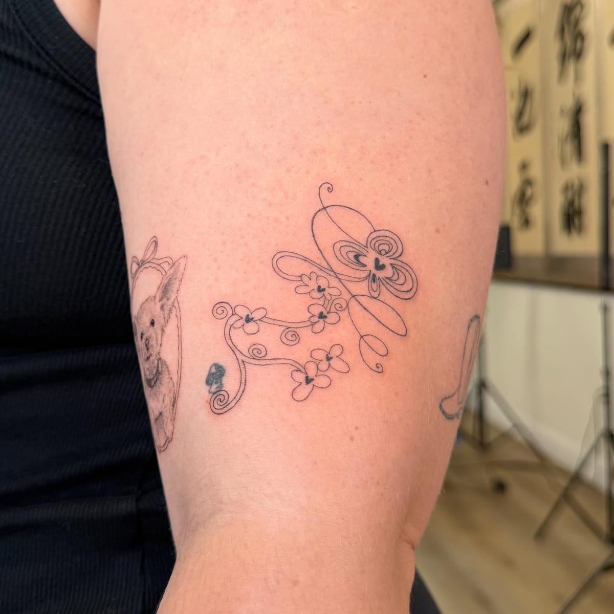 Swirling butterfly with flowers and vines, fine line tattoo