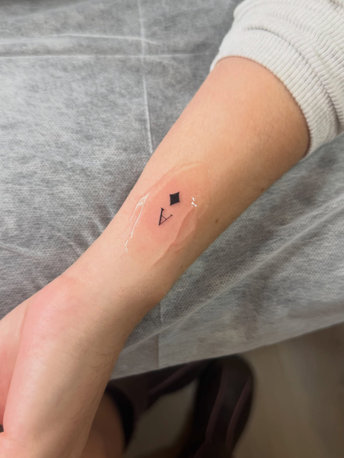 Tiny diamond suit and letter A, fine line tattoo