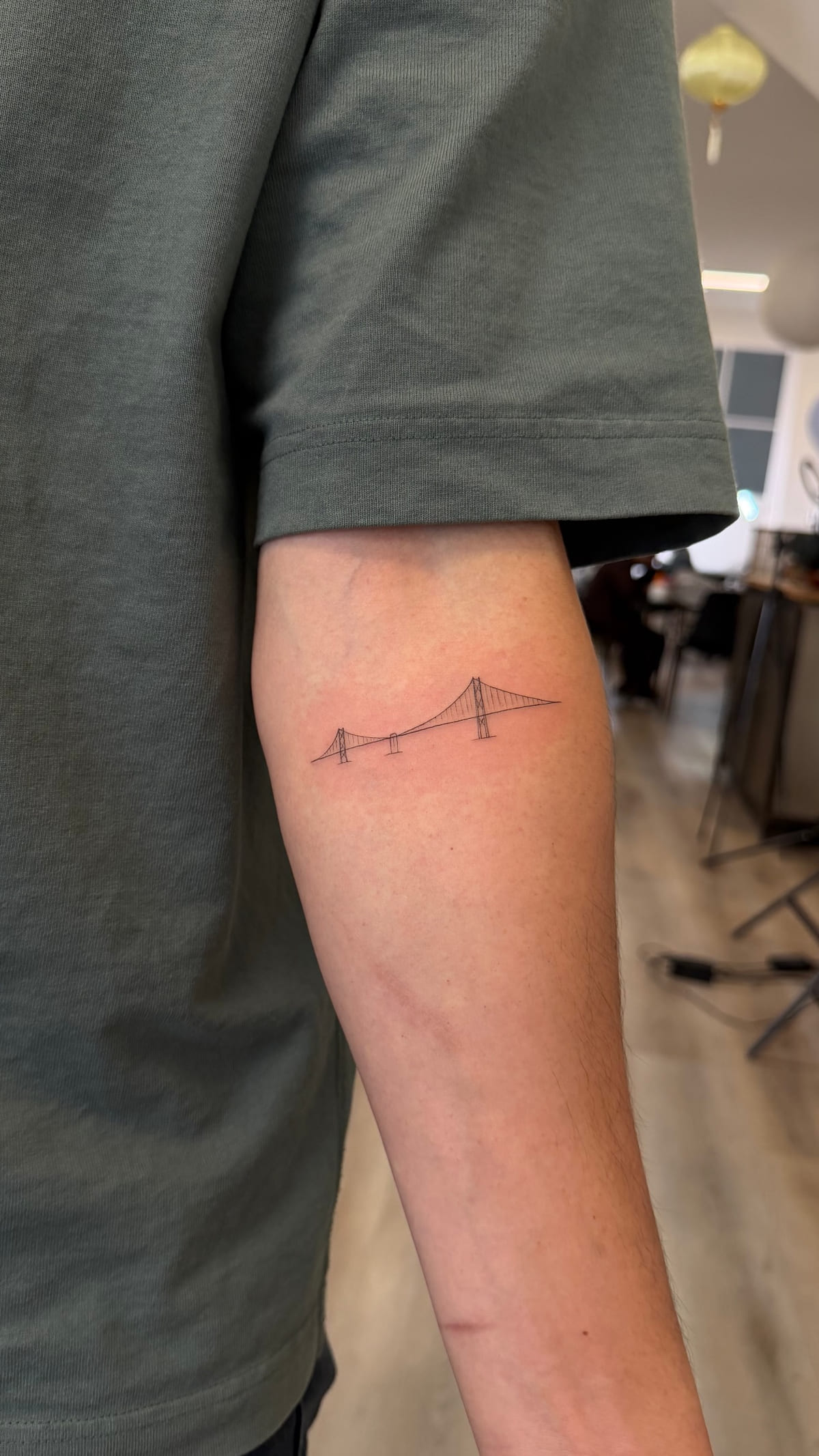 Very small Golden Gate Bridge in fine line on a forearm, fine line tattoo