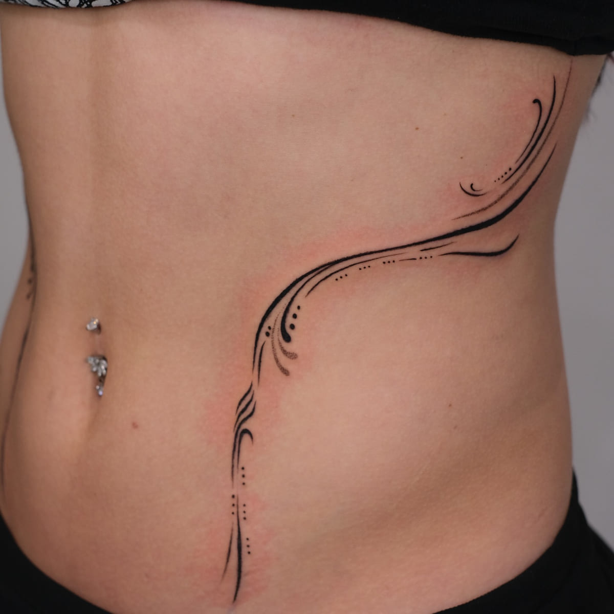 Ornamental flowing lines framing both sides of the abdomen, another view