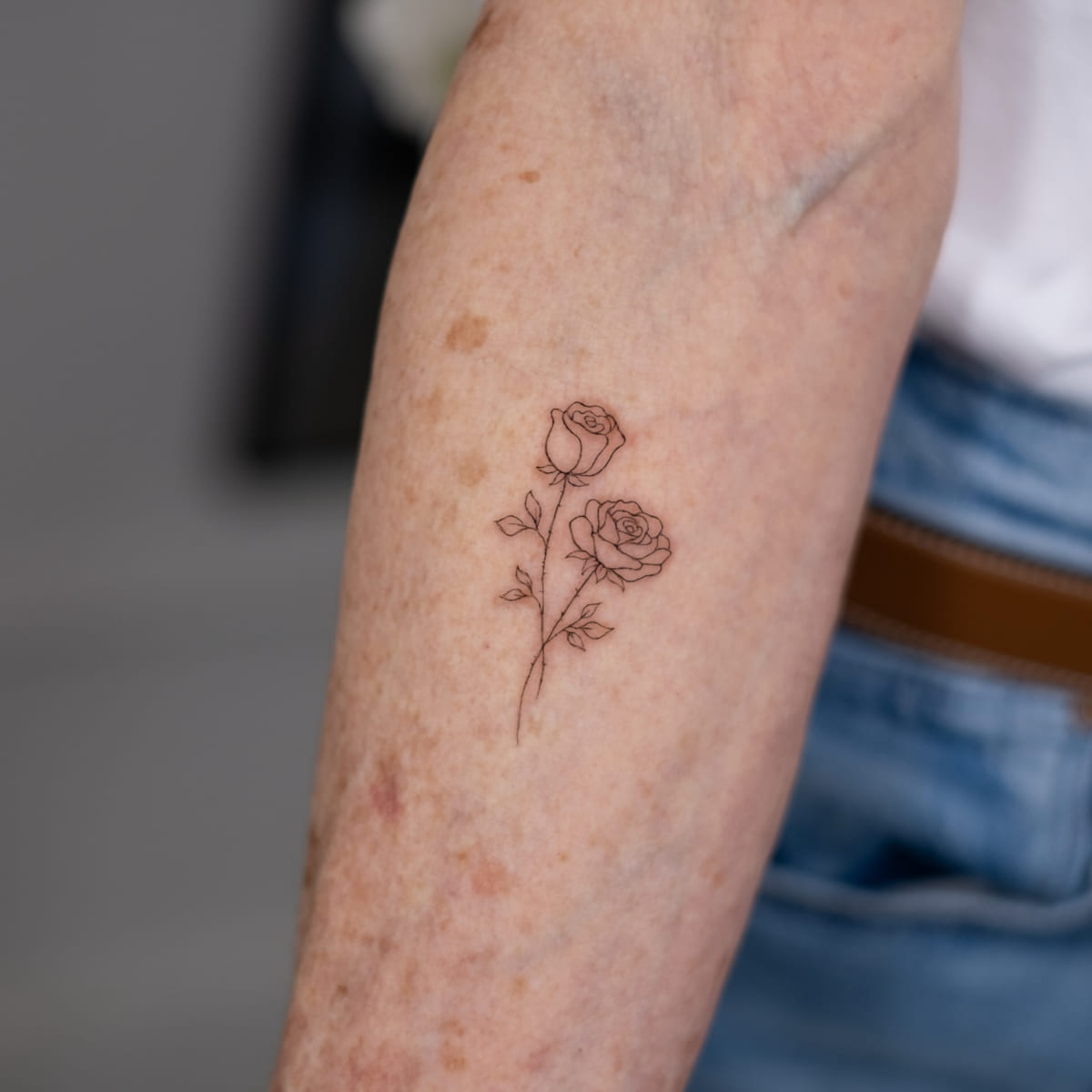 Two roses on one stem, fine line tattoo