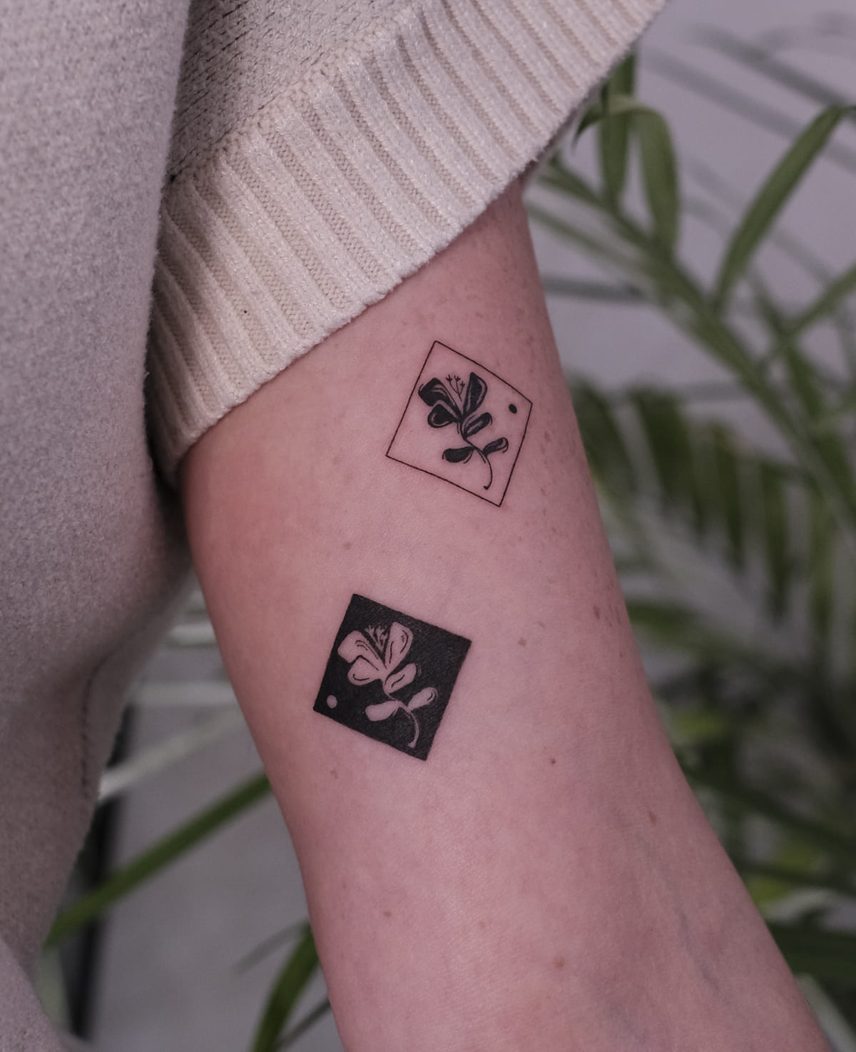 Two flower squares, one outlined and one solid with negative space, fine line tattoo
