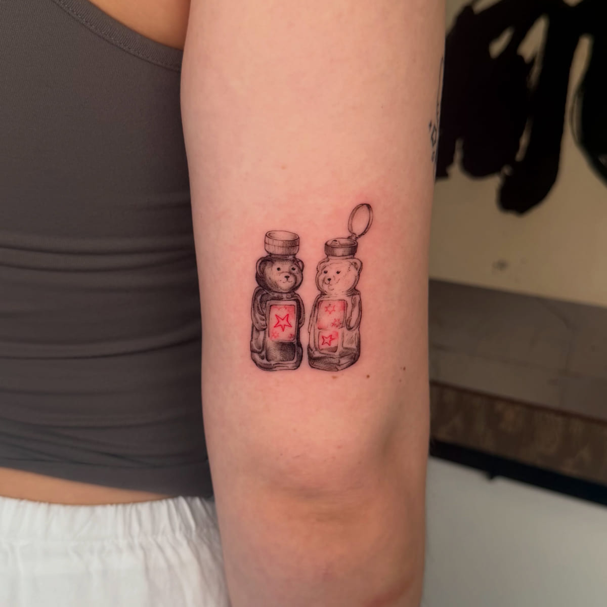 Two honey bear bottles, red labels with stars, fine line tattoo