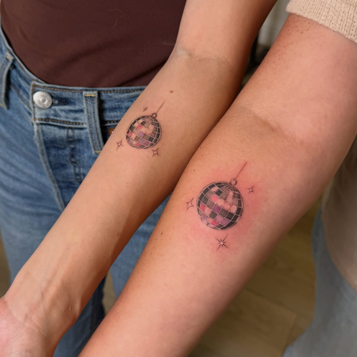 Matching disco balls on two forearms, fine line tattoo