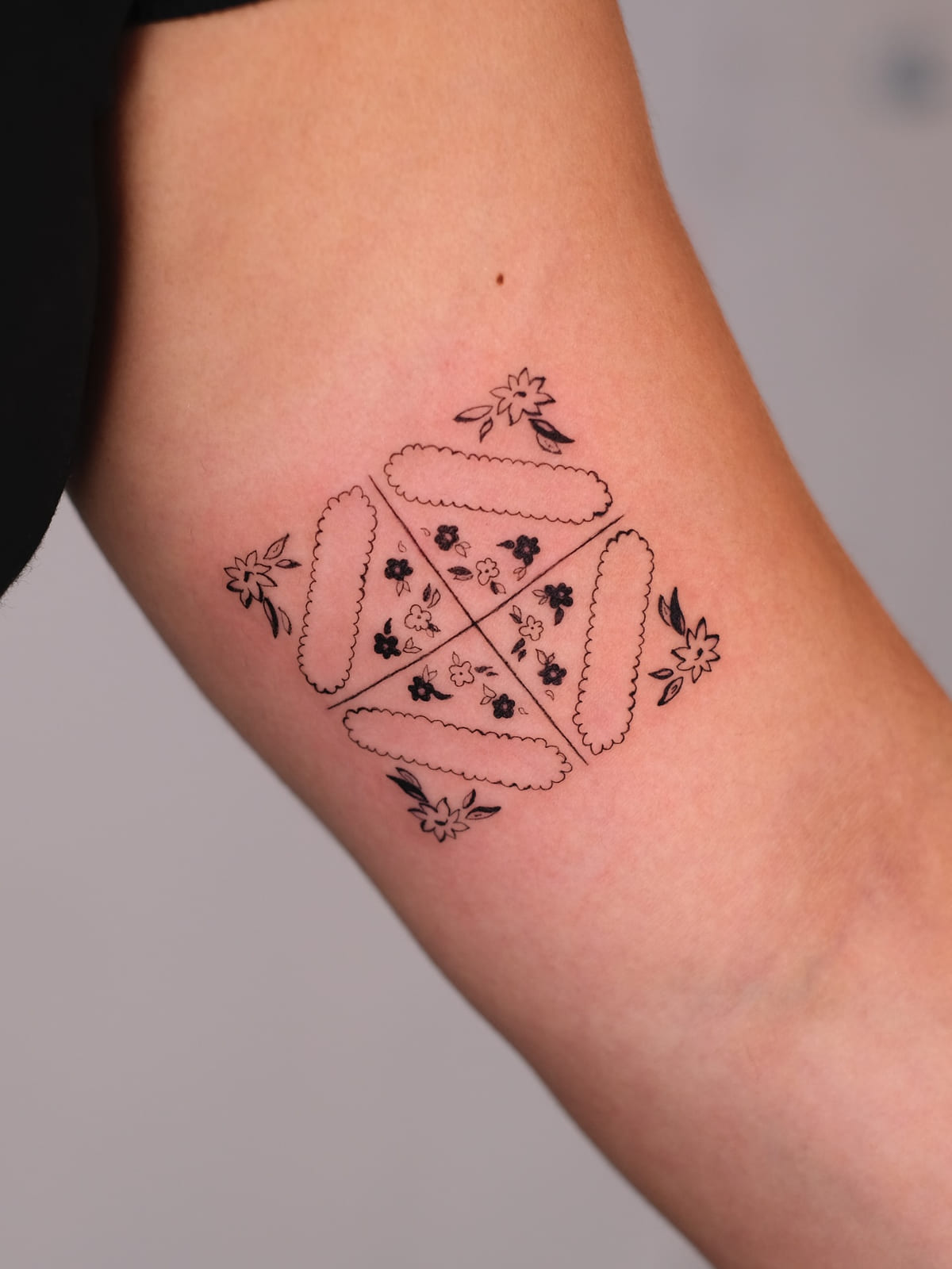 Square of four scalloped tiles with small flowers, fine line tattoo