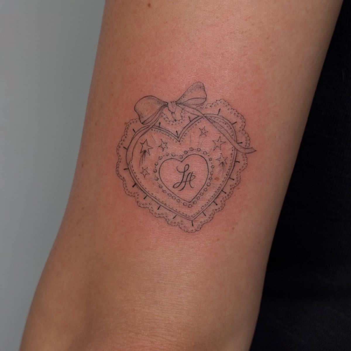 Lace valentine heart with a bow, script initials inside, fine line tattoo