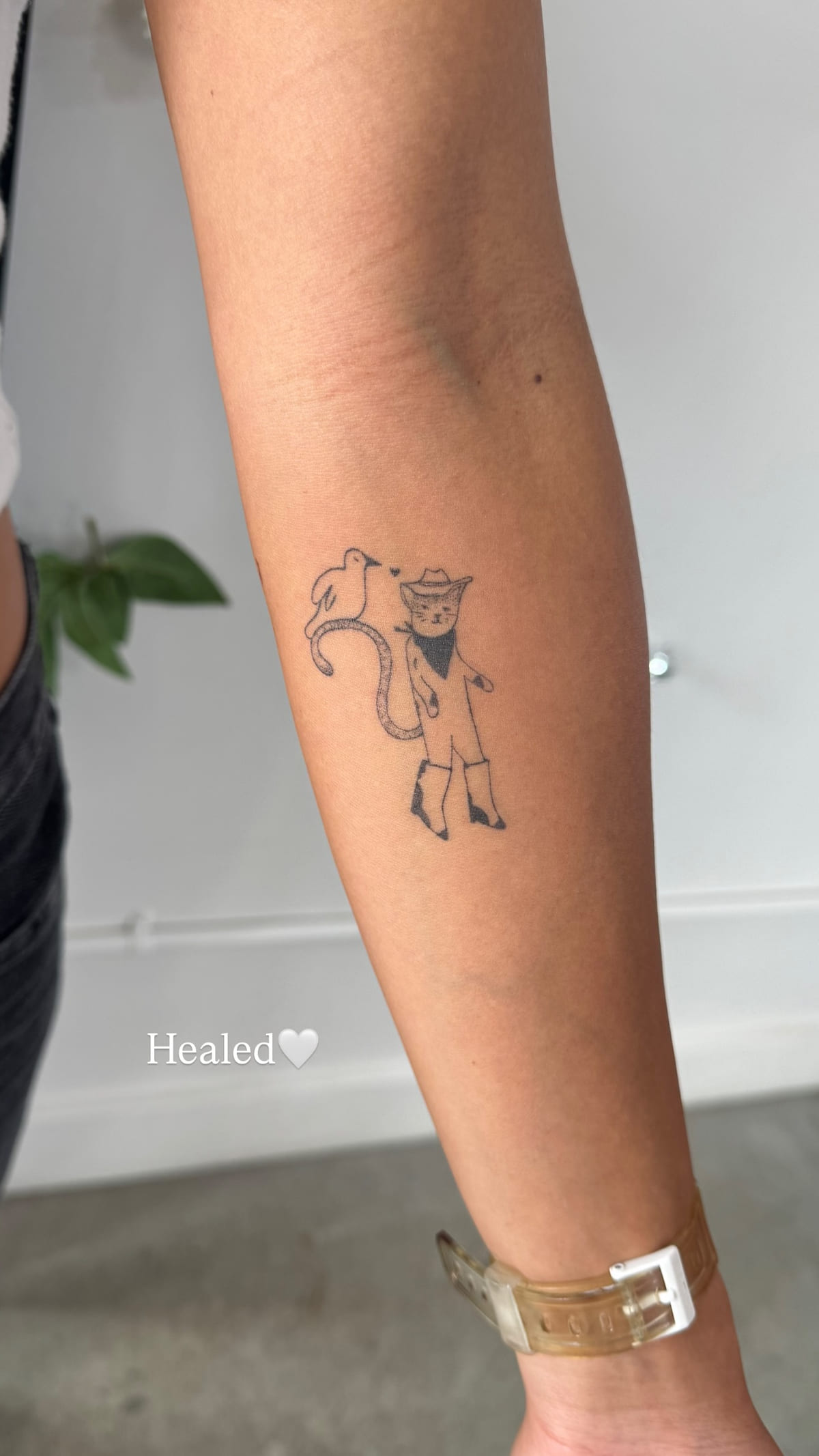 Small cowboy character on a forearm, healed fine line tattoo