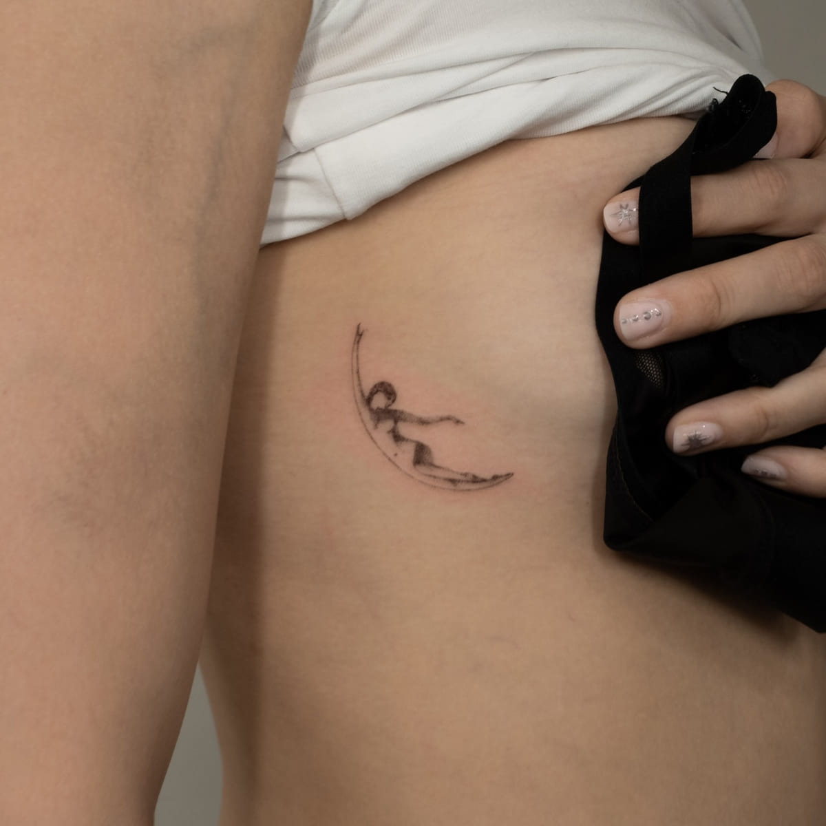Crescent moon holding a small landscape, fine line tattoo