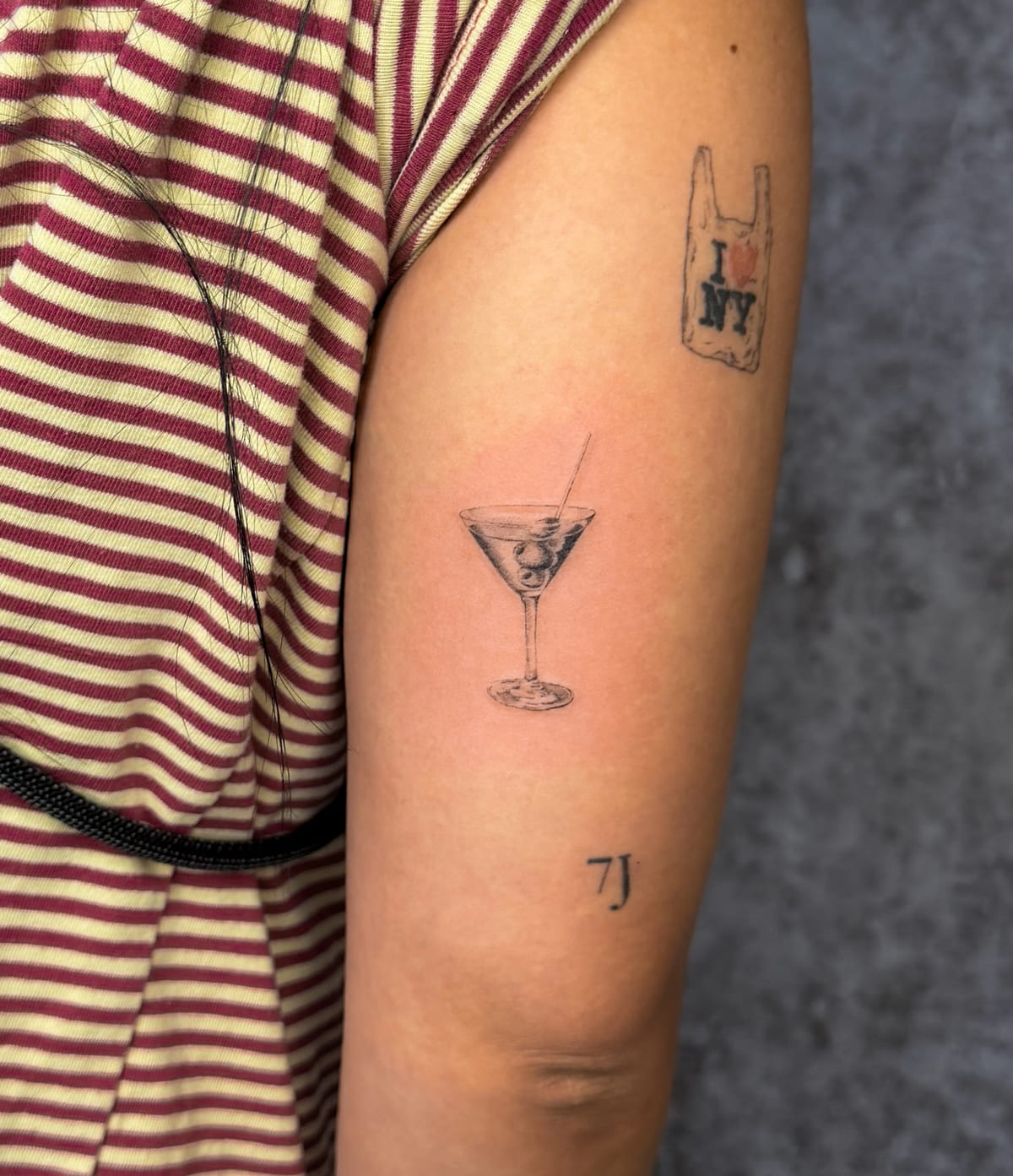 Martini glass with an olive, micro realism, fine line tattoo
