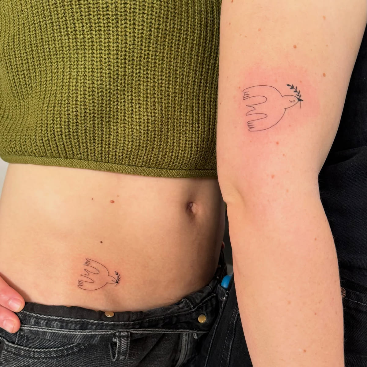 Two line drawn doves, one on the arm and one on the lower belly, fine line tattoo