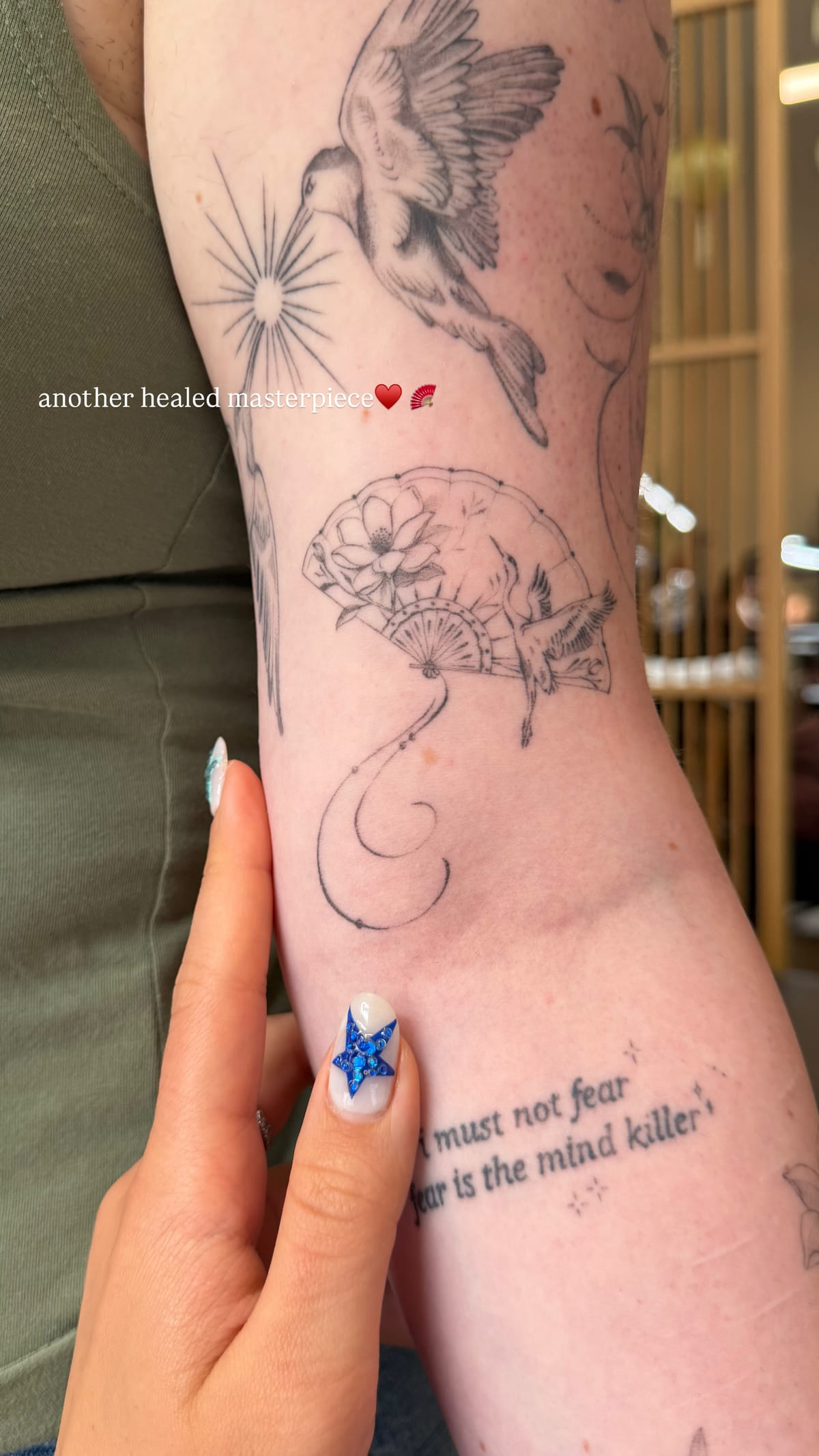 Bird, fan with a lotus, and a quote on a forearm, healed fine line tattoo, healed