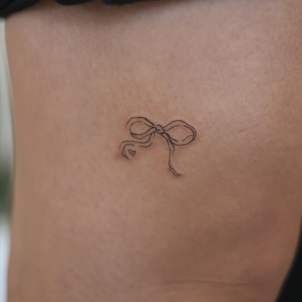 Ribbon bow with a tiny heart, fine line tattoo