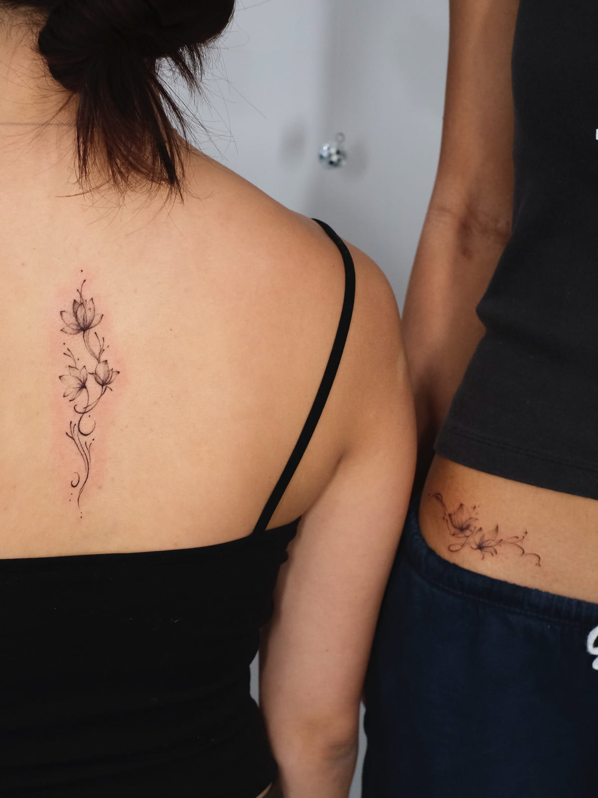 Lilies down the upper spine, fine line tattoo