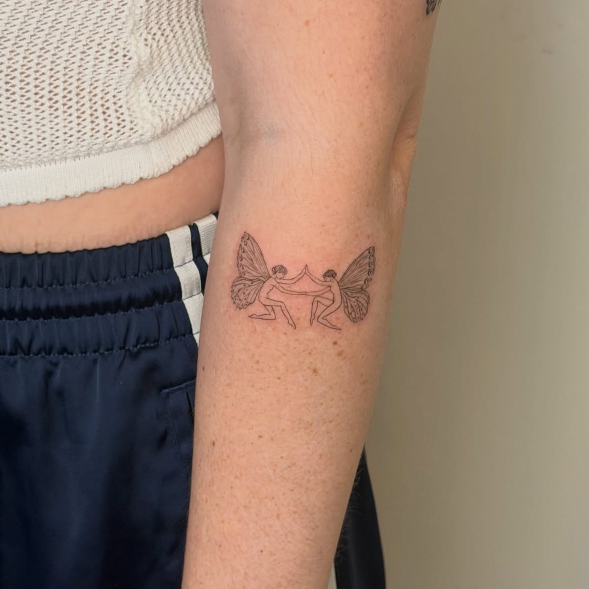 Two fairies touching hands, fine line tattoo