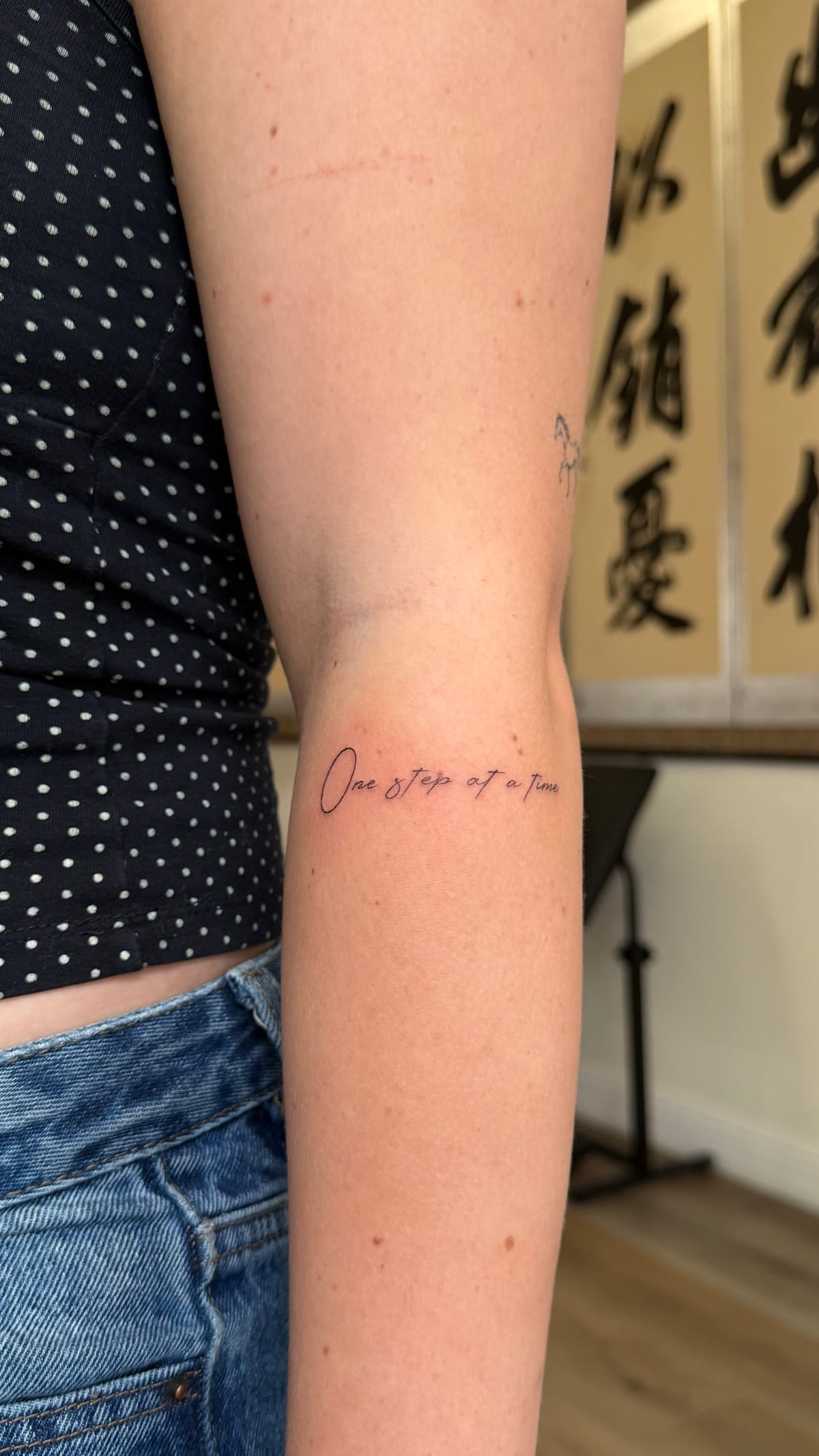 Line of fine script on an inner arm, healed fine line tattoo