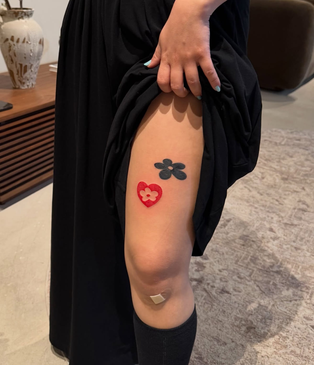Solid black flower and solid red heart with a flower, fine line tattoo