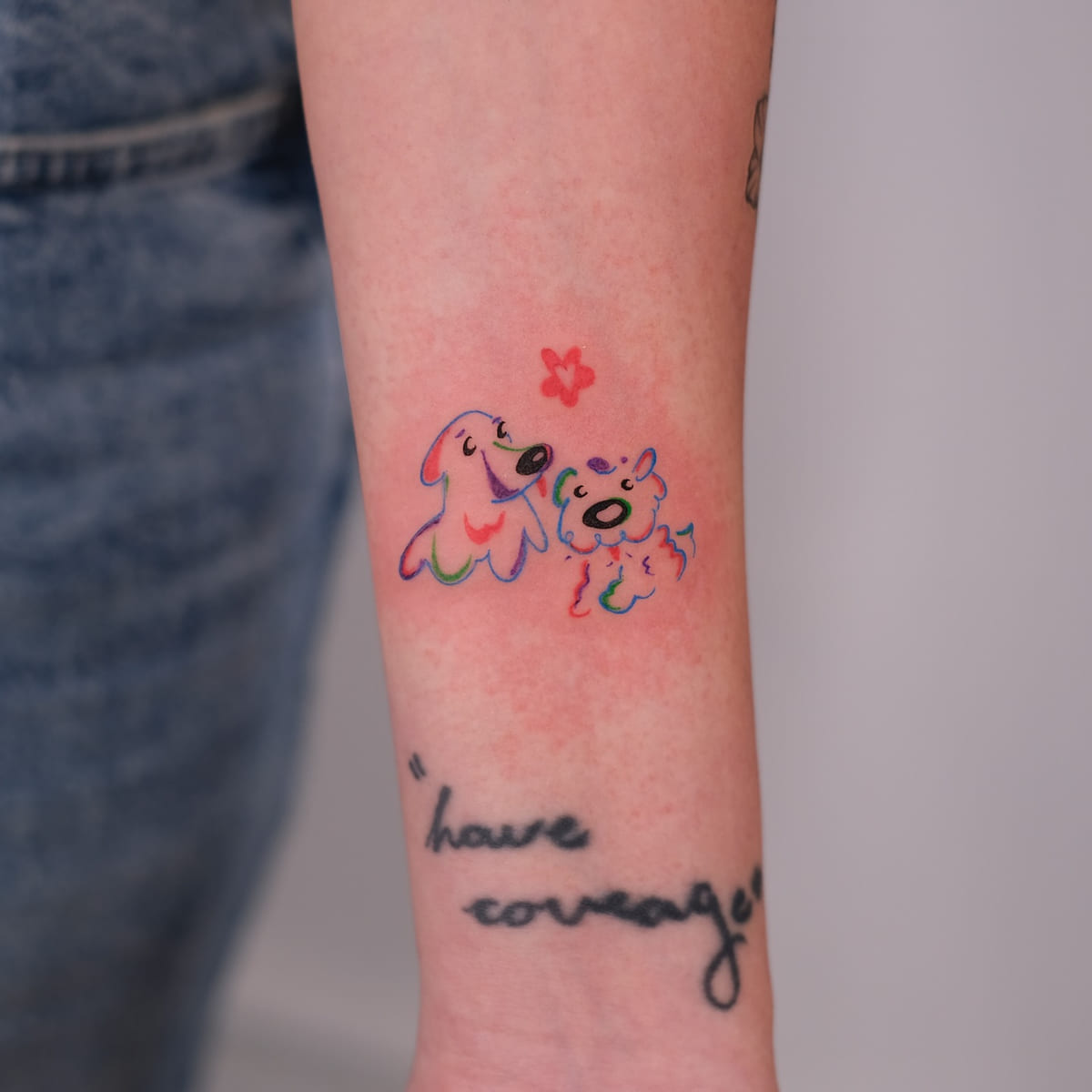 Two cartoon dogs in rainbow line with a red flower, fine line tattoo