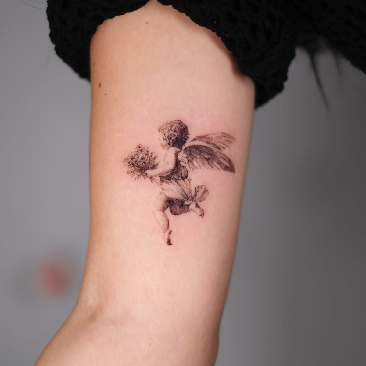 Cherub carrying a bouquet, micro realism, fine line tattoo