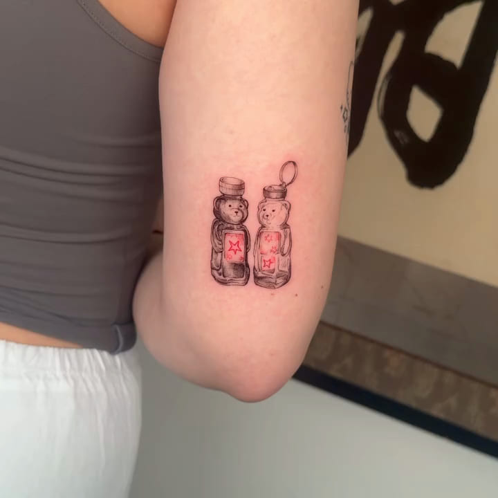 Two honey bear bottles, red labels with stars, fine line tattoo