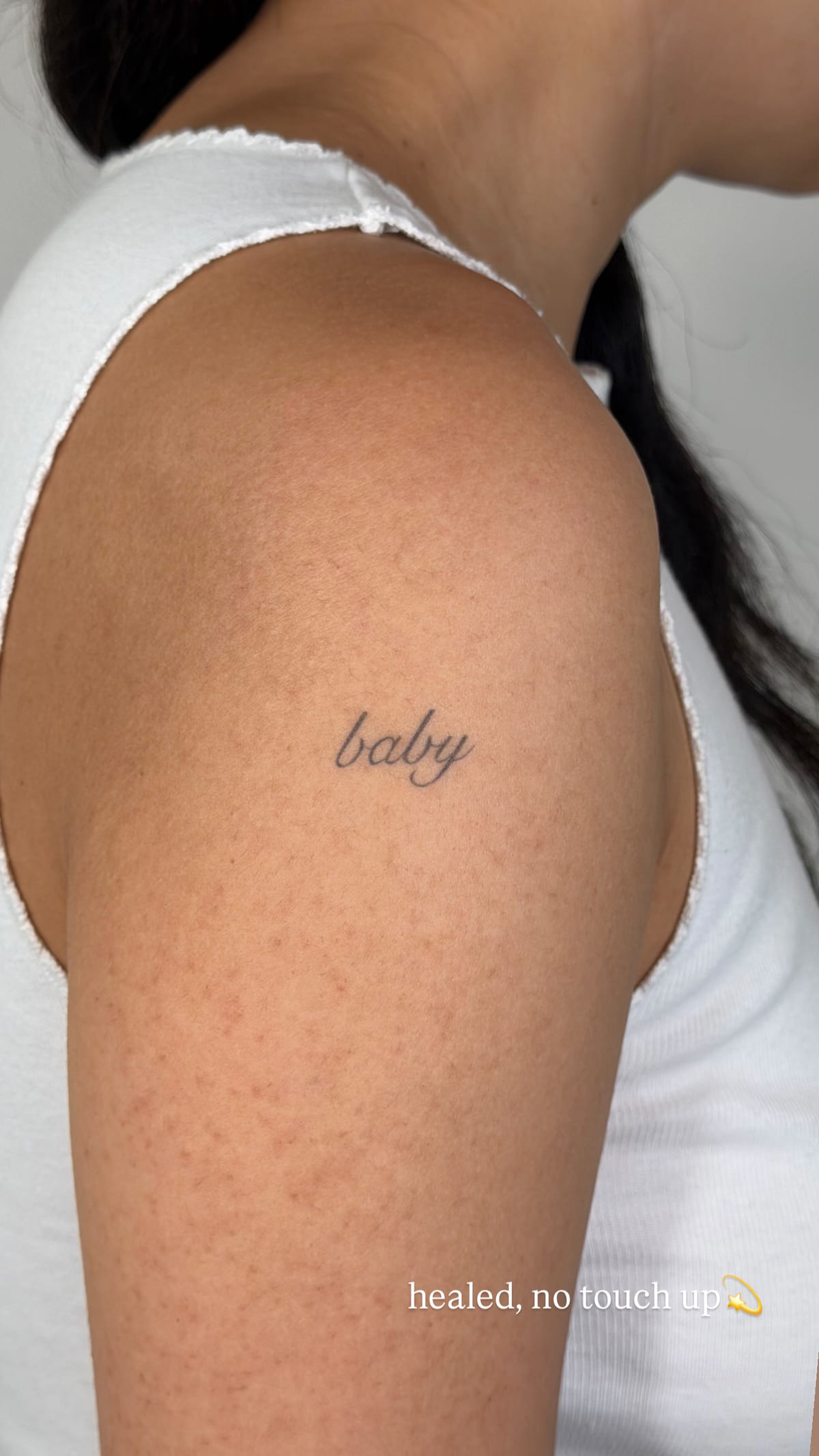 The word baby in fine script, healed fine line tattoo, healed