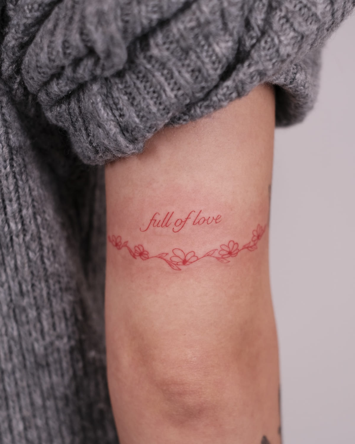 Armband of a flower garland with the words full of love, fine line tattoo