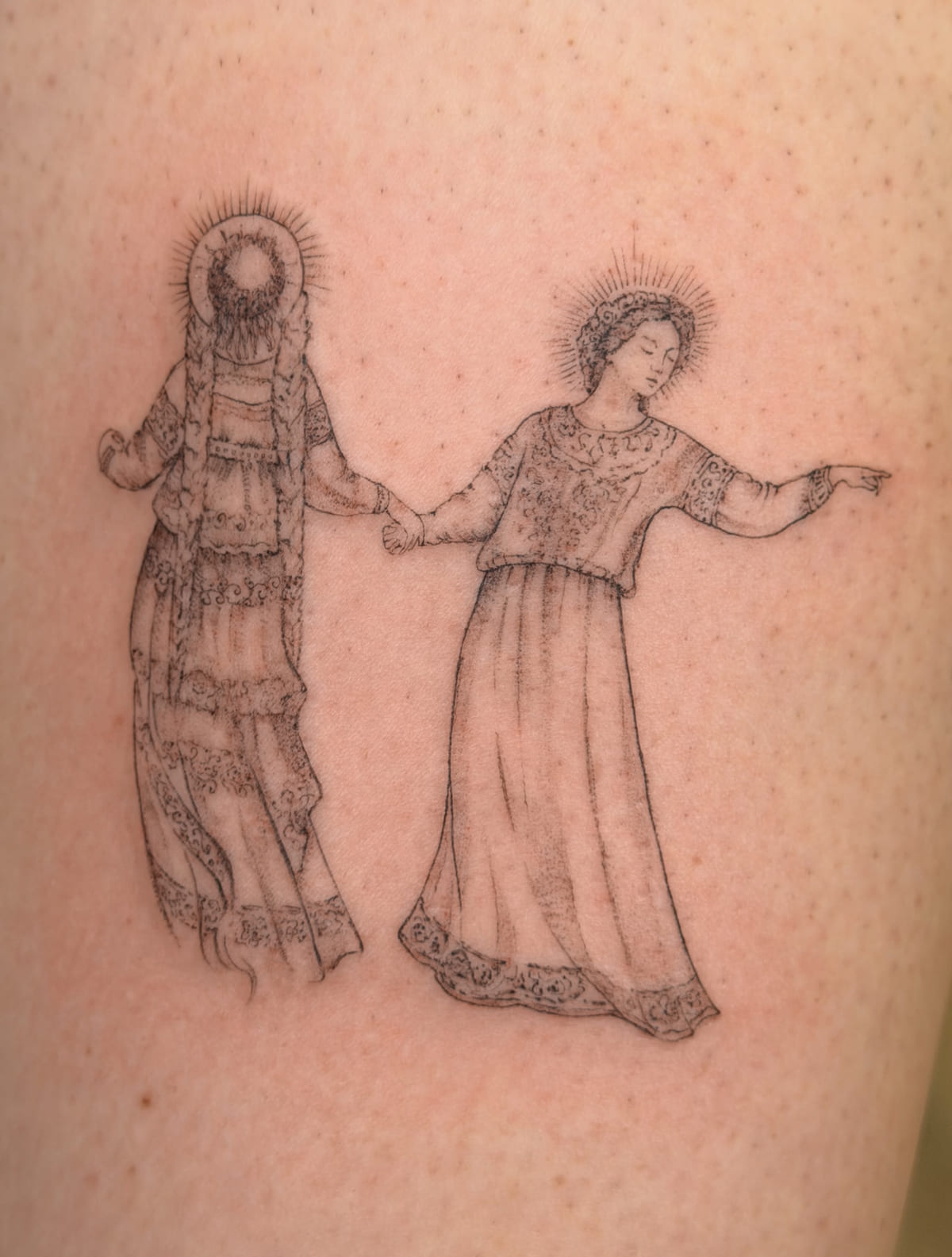 Two haloed women in embroidered folk dresses holding hands, fine line tattoo