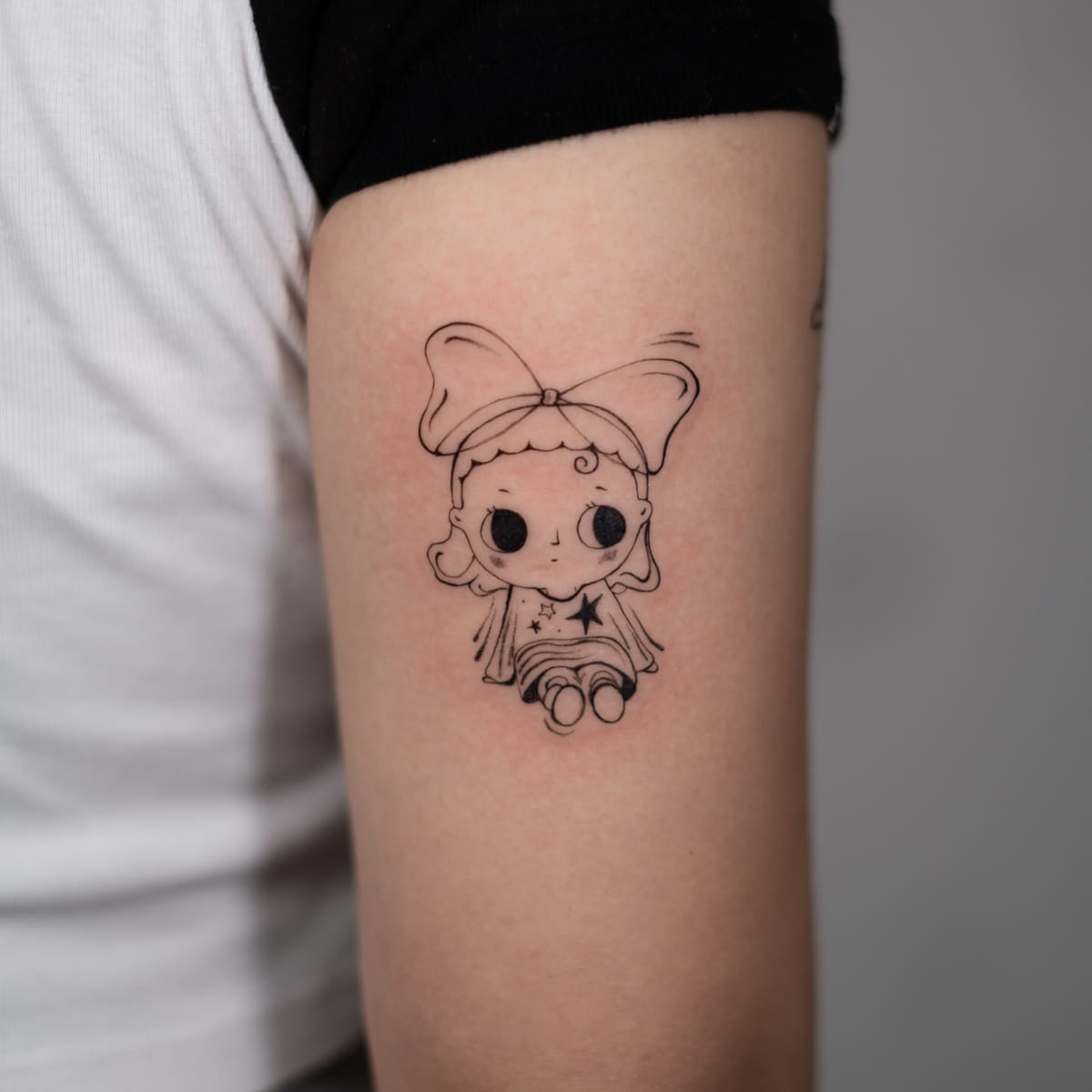 Doll with a big bow, sitting, fine line tattoo