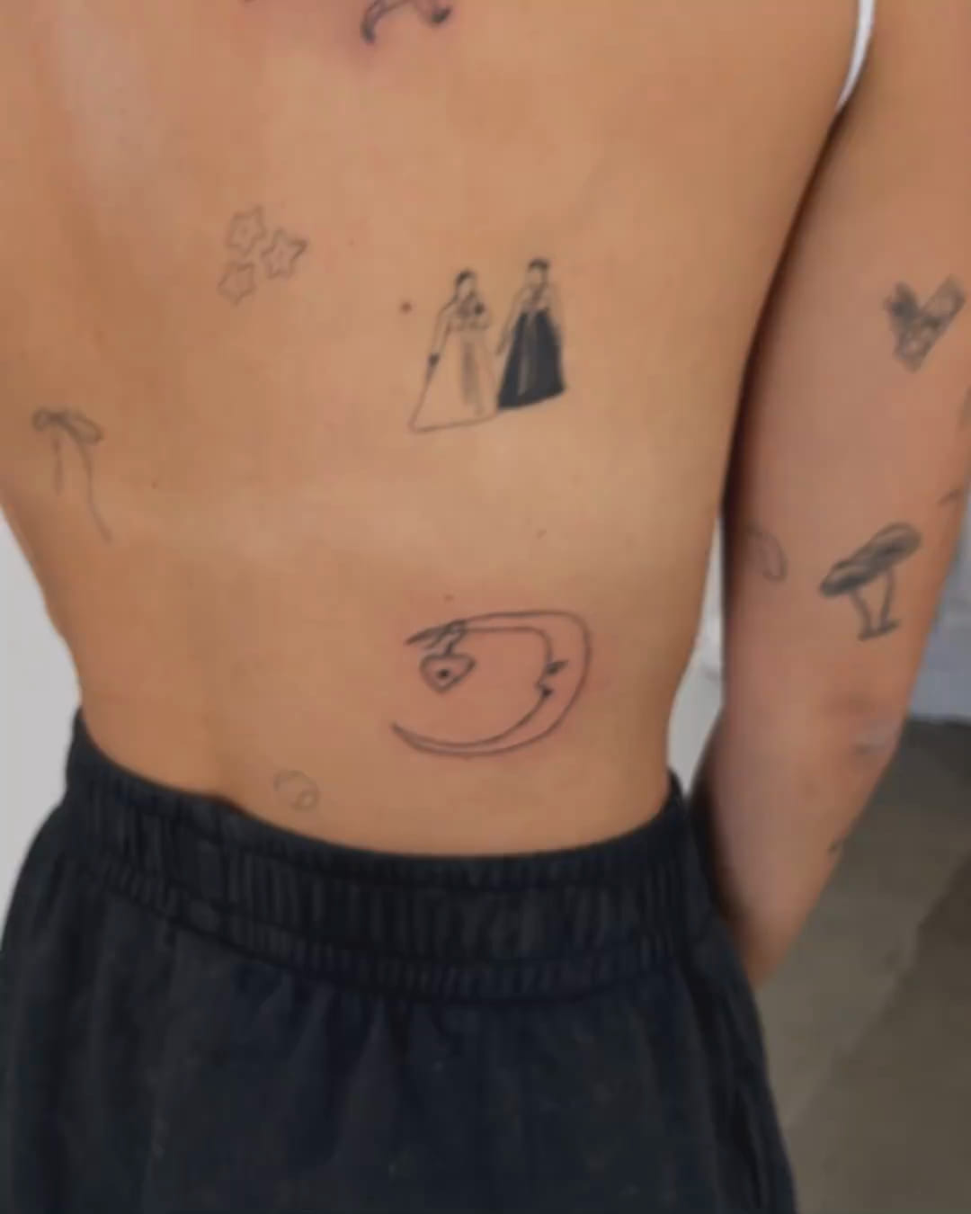 Crescent moon holding a heart locket, on the lower back, fine line tattoo