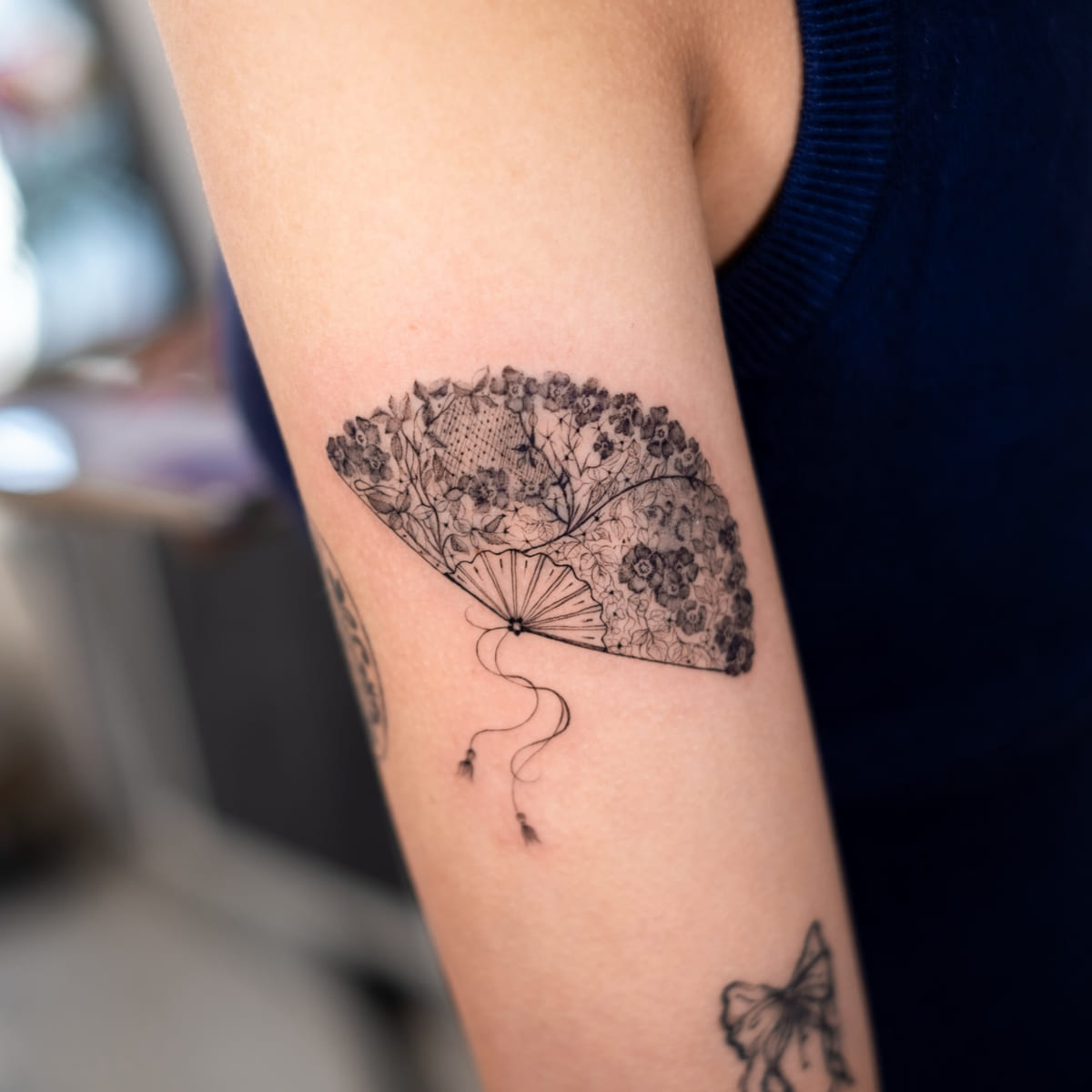 Lace hand fan with flowers and a tassel, fine line tattoo