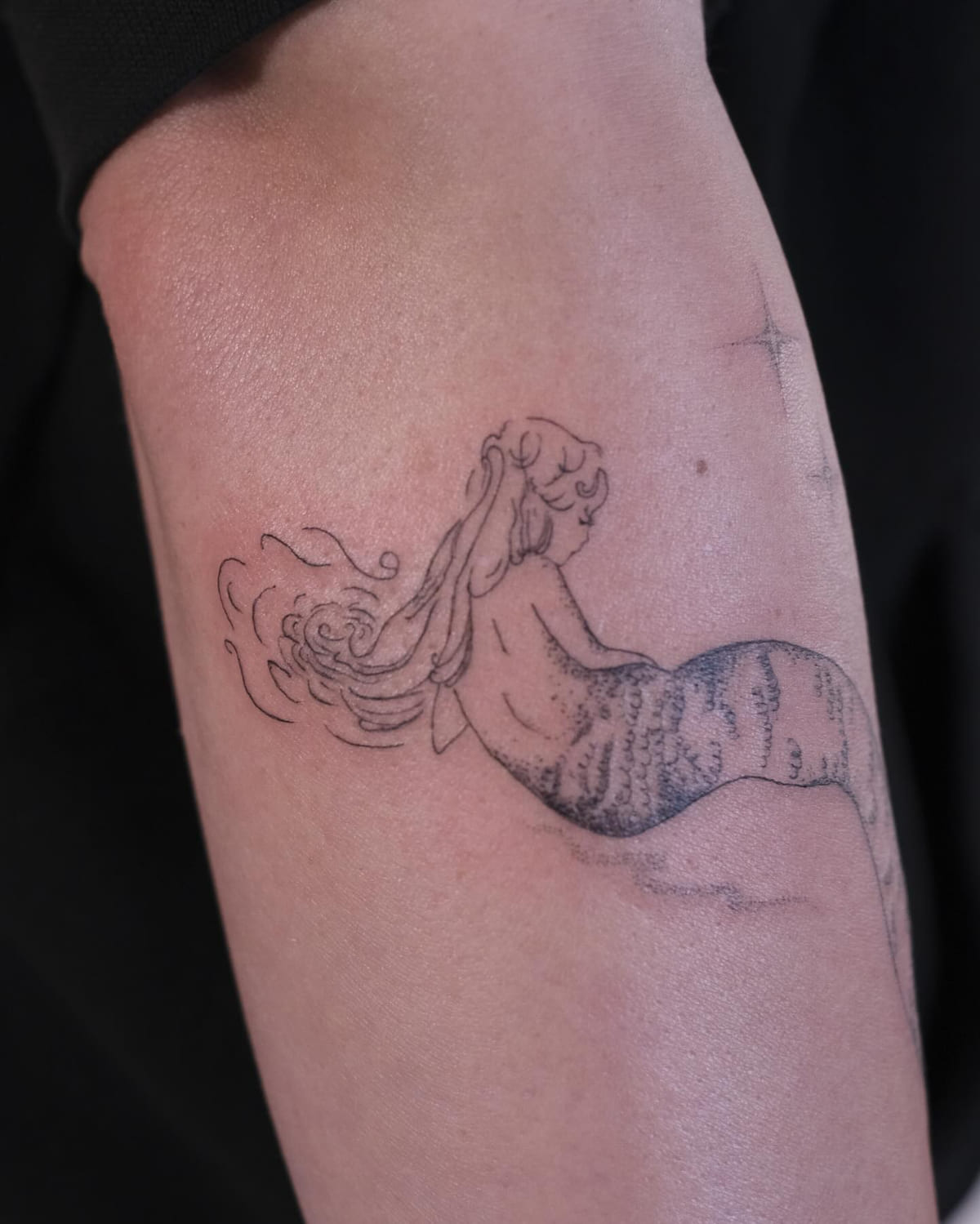 Mermaid seen from behind with wind swept hair and sparkles, another view