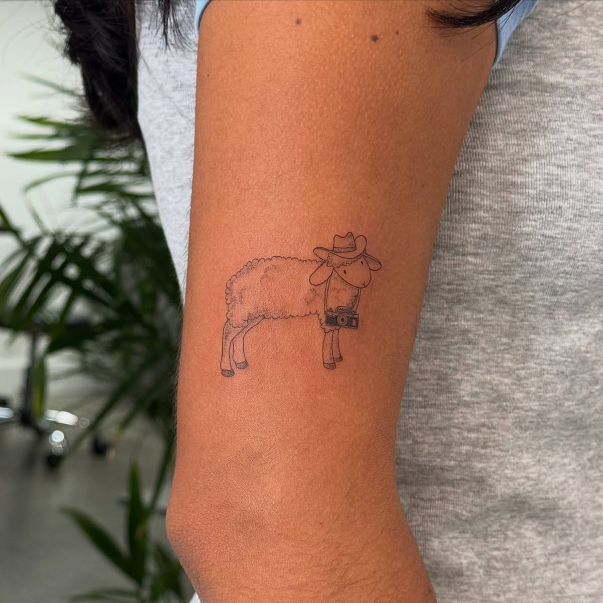 Sheep in a cowboy hat with a camera, fine line tattoo