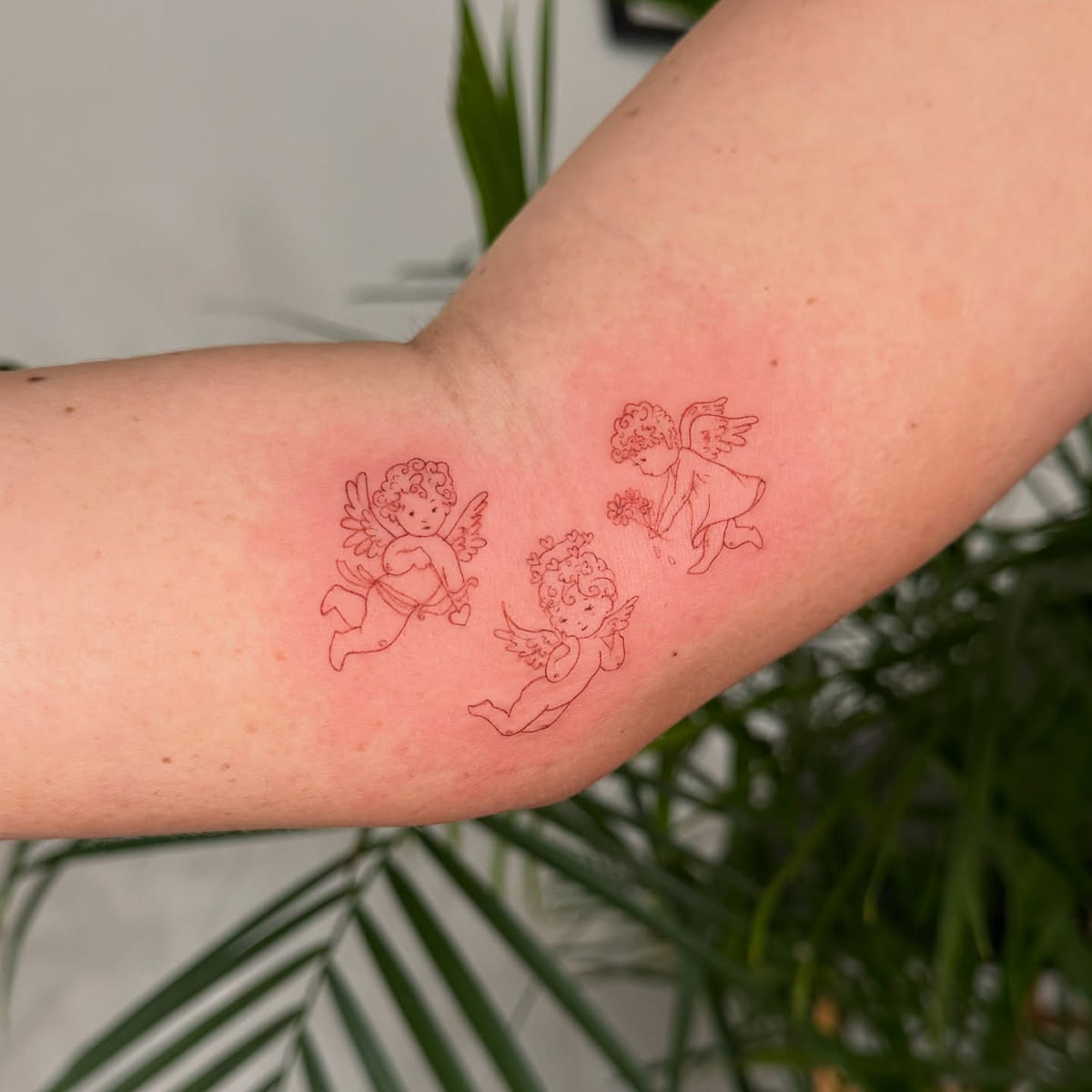 Three cherubs in red line, fine line tattoo