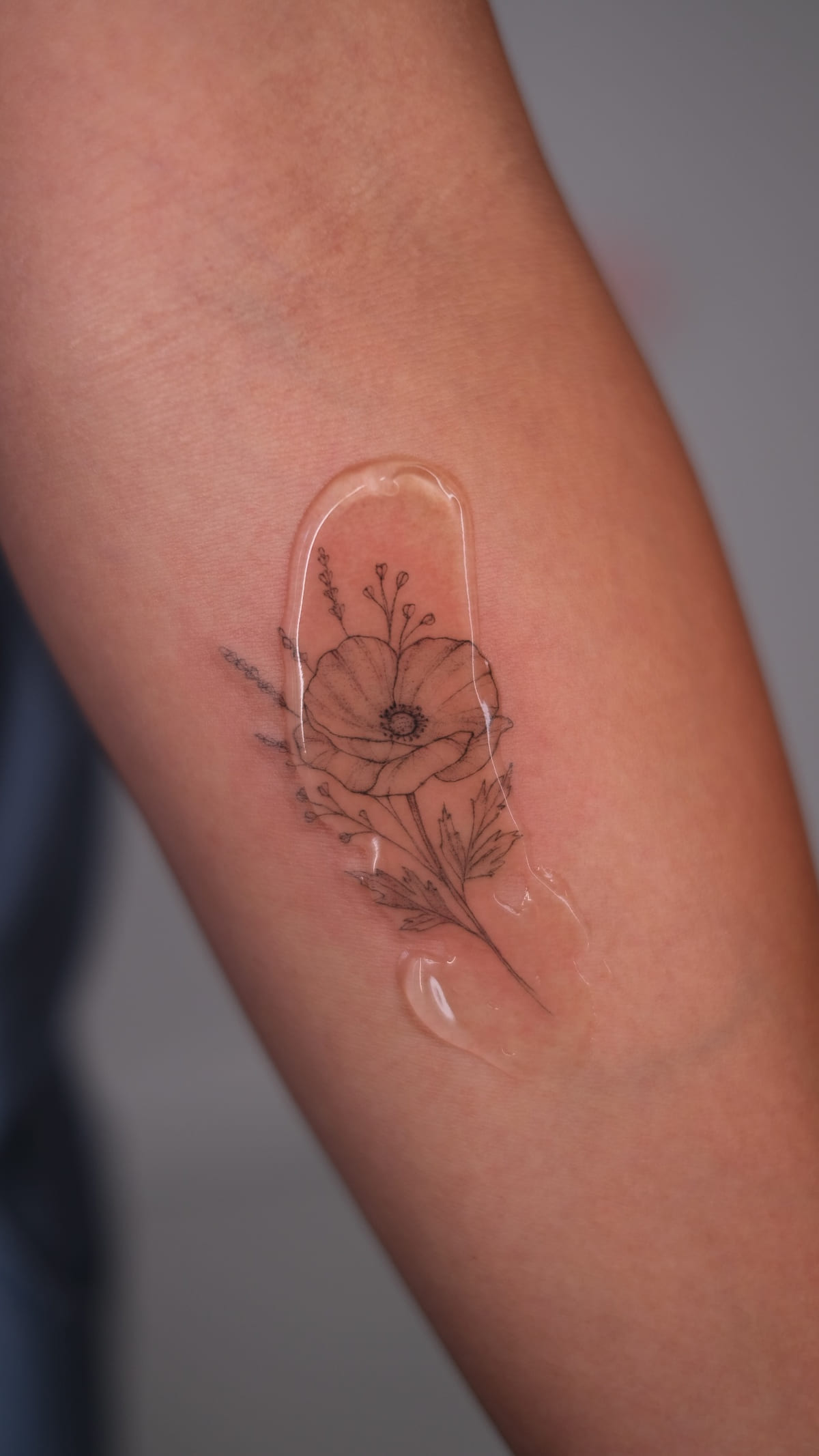 A California poppy on a forearm under the clear second skin film, right after the session